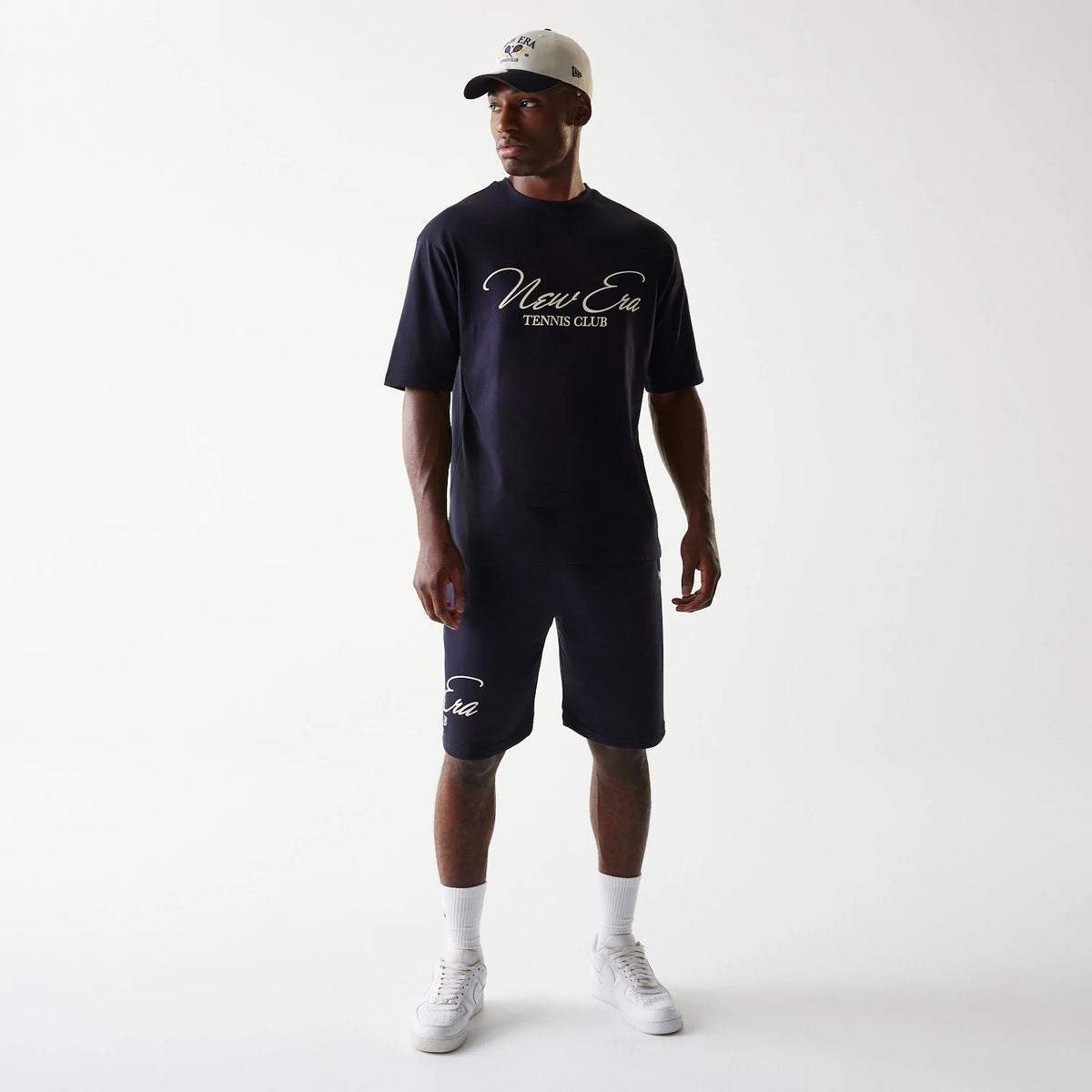 New Era Navy Oversized T-Shirt, front view on-model displaying the white script New Era Tennis Club logo across the chest, styled with matching navy shorts featuring the logo above the left knee.
