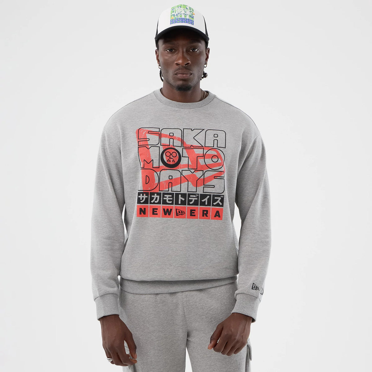 New Era Sakamoto Days Netflix Grey Crew Neck Sweater, front view on a model with a graphic print featuring red and black text and Japanese characters, with the New Era logo on the sleeve.