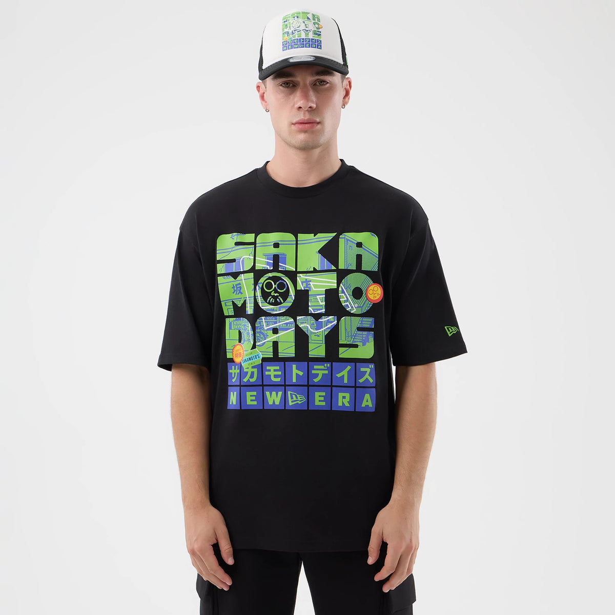 New Era Sakamoto Days Netflix Black T-Shirt, front view showing green and blue graphics featuring text and images across the chest, a small New Era embroidered logo on the sleeve, and styled casually on a model.