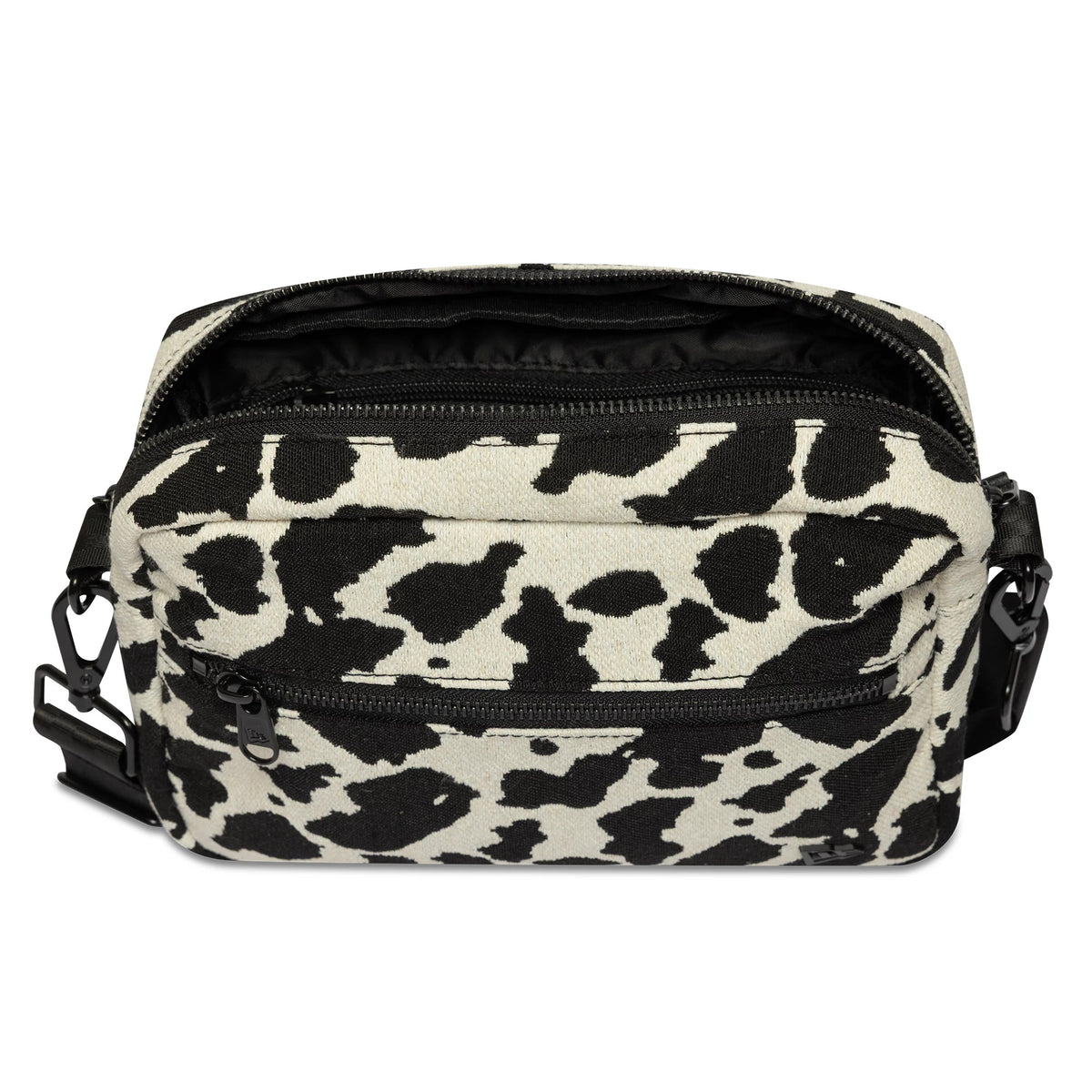 New Era Cow Jacquard Light Beige Waist Bag, open view showing the cow print pattern in black and light beige, with a zip closure on the top, a front zip pocket, and a debossed New Era logo on the front.