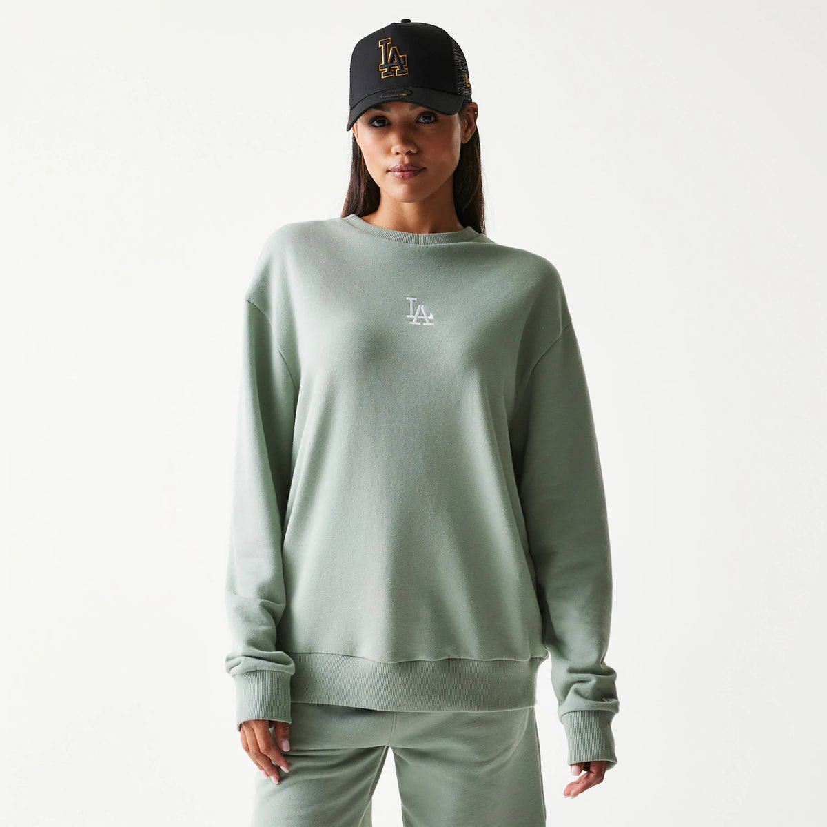 New Era LA Dodgers MLB Midi Pastel Green Oversized Crew Neck Sweater, front view on a model pairing the sweater with relaxed fit joggers, showing the white embroidered LA logo on the chest and ribbed cuffs and hem.