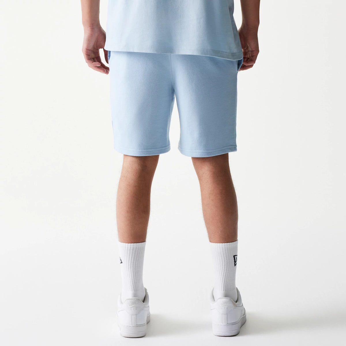 New Era New York Yankees MLB League Essential Midi Pastel Blue Shorts, back view on a model with matching pastel tones, showing the relaxed fit and knee-length cut with along the hem.