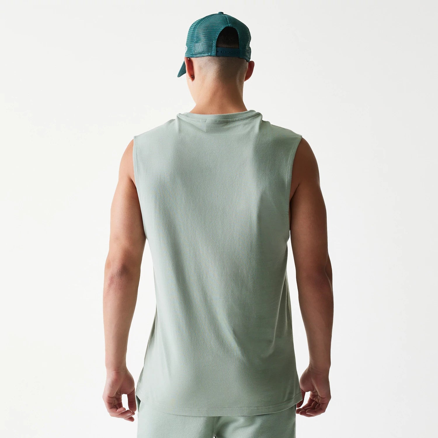 New Era LA Dodgers MLB Pastel Green Sleeveless T-Shirt, back view on-model showing the plain pastel green fabric with wide armholes, styled with a matching pastel green cap worn backwards.