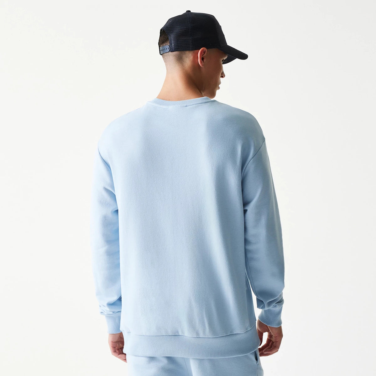 New Era New York Yankees MLB Midi Blue Oversized Crew Neck Sweater, back view on a model showing the plain light blue fabric with ribbed cuffs and hem, offering a relaxed fit and a casual sporty look.