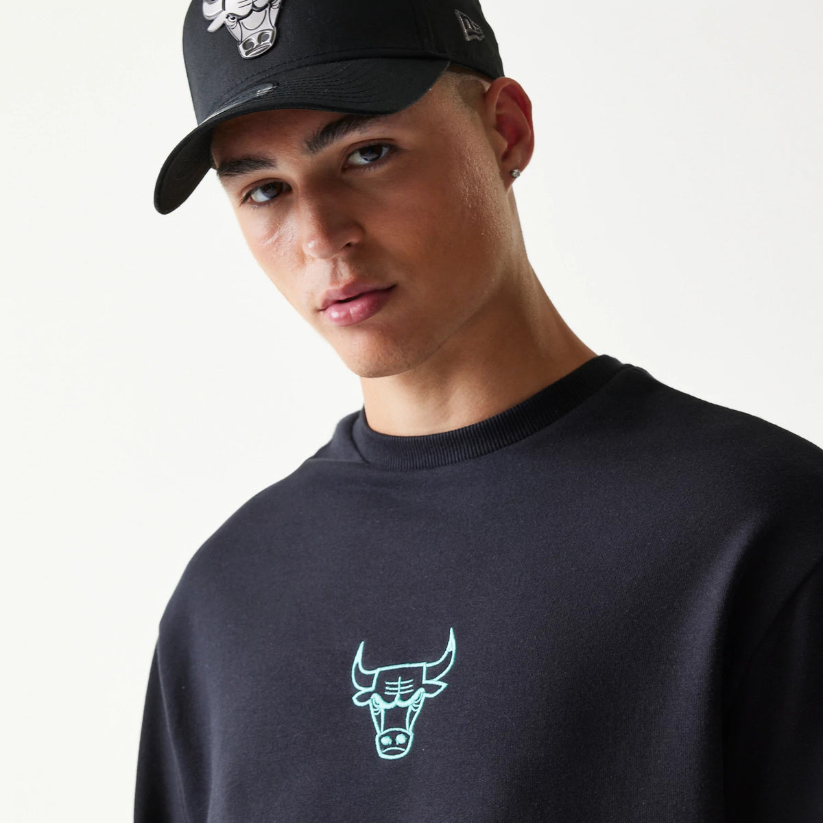 New Era Chicago Bulls NBA Black Oversized Crew Neck Sweater, on-model view showing the light blue embroidered Bulls logo centred on the chest with a ribbed collar and relaxed fit of the black fabric.