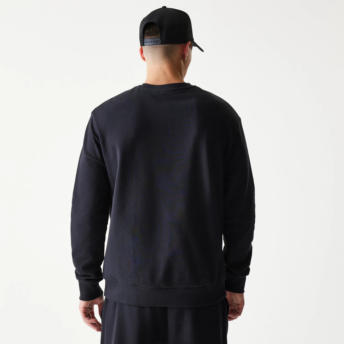 New Era Chicago Bulls NBA Black Oversized Crew Neck Sweater, back view on a model showing the simple plain design with ribbed cuffs and hem, paired with matching black track pants for a coordinated look.