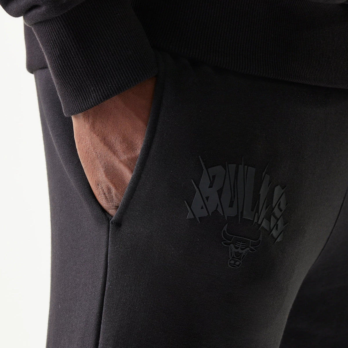 New Era Chicago Bulls NBA Black Straight Leg Joggers, side view showing the hand in the front pocket and the black embossed Bulls logo on the upper thigh of the black fabric near the waistband.