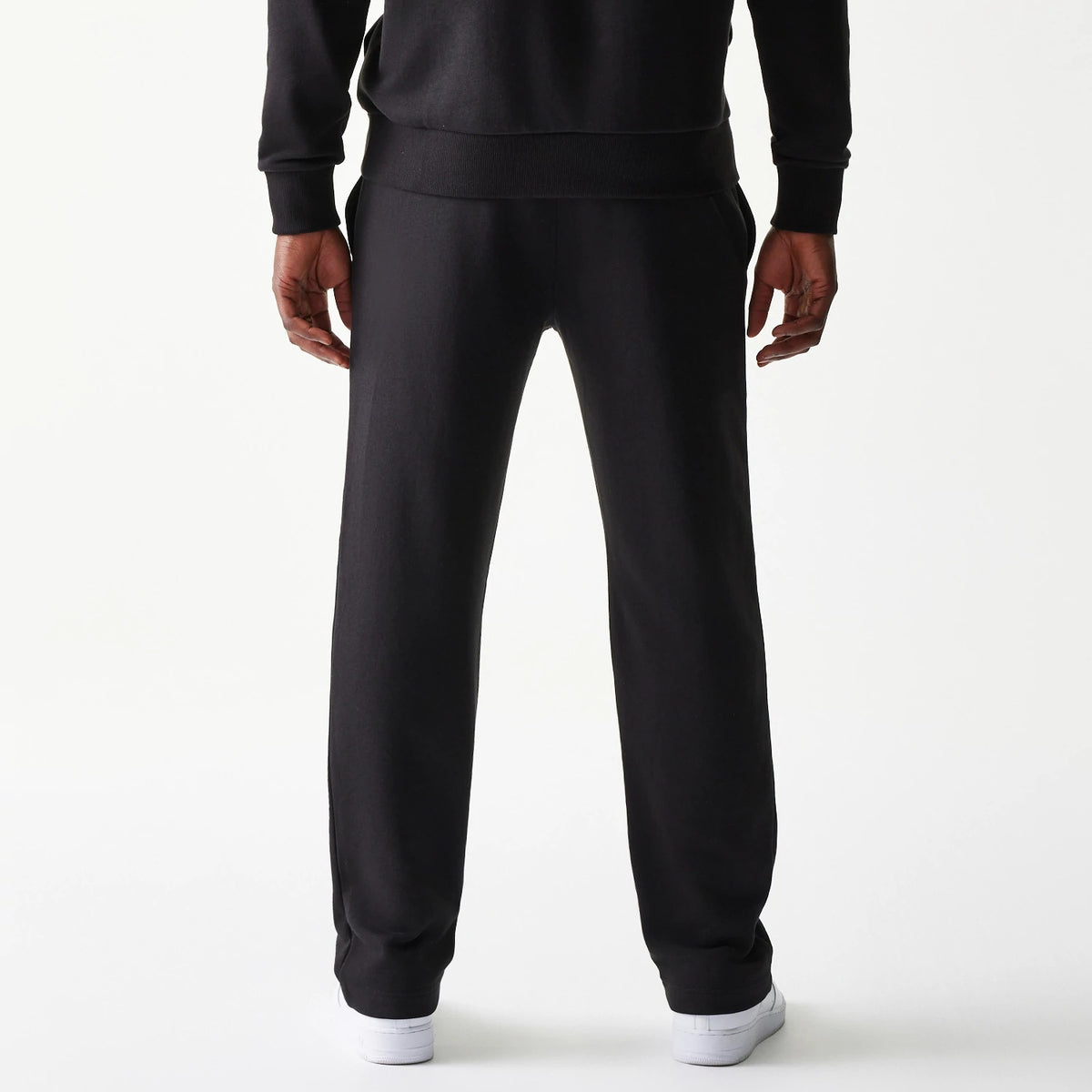 New Era Chicago Bulls NBA Black Straight Leg Joggers, back view on a model showing the plain black design with an elastic waistband, straight relaxed fit, and white trainers, highlighting the simplicity and comfort of the joggers.