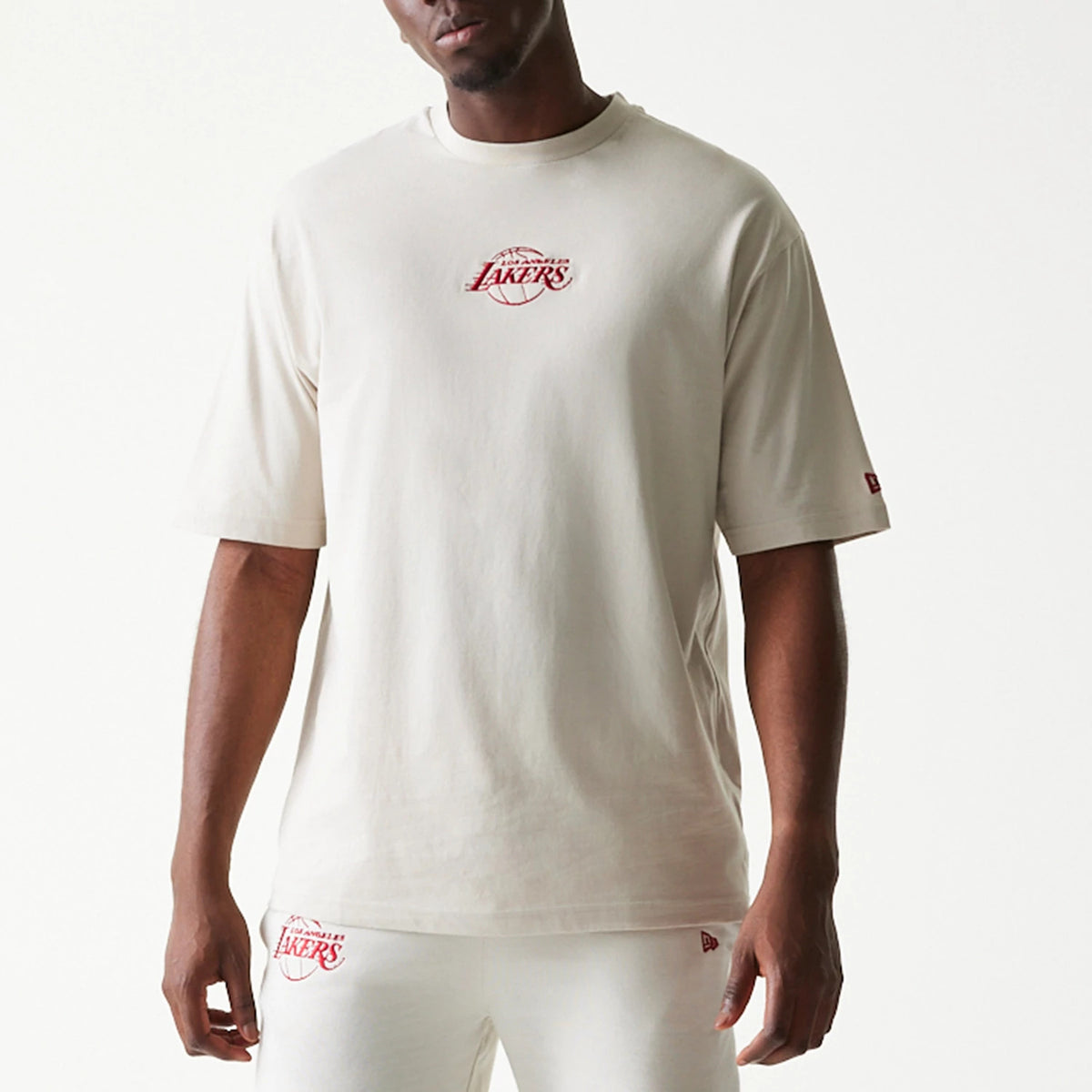 New Era LA Lakers NBA League Essential Cream Oversized T-Shirt, front view on a model showing the red printed LA Lakers logo centrally on the chest, with a small red New Era embroidered logo on the left sleeve.