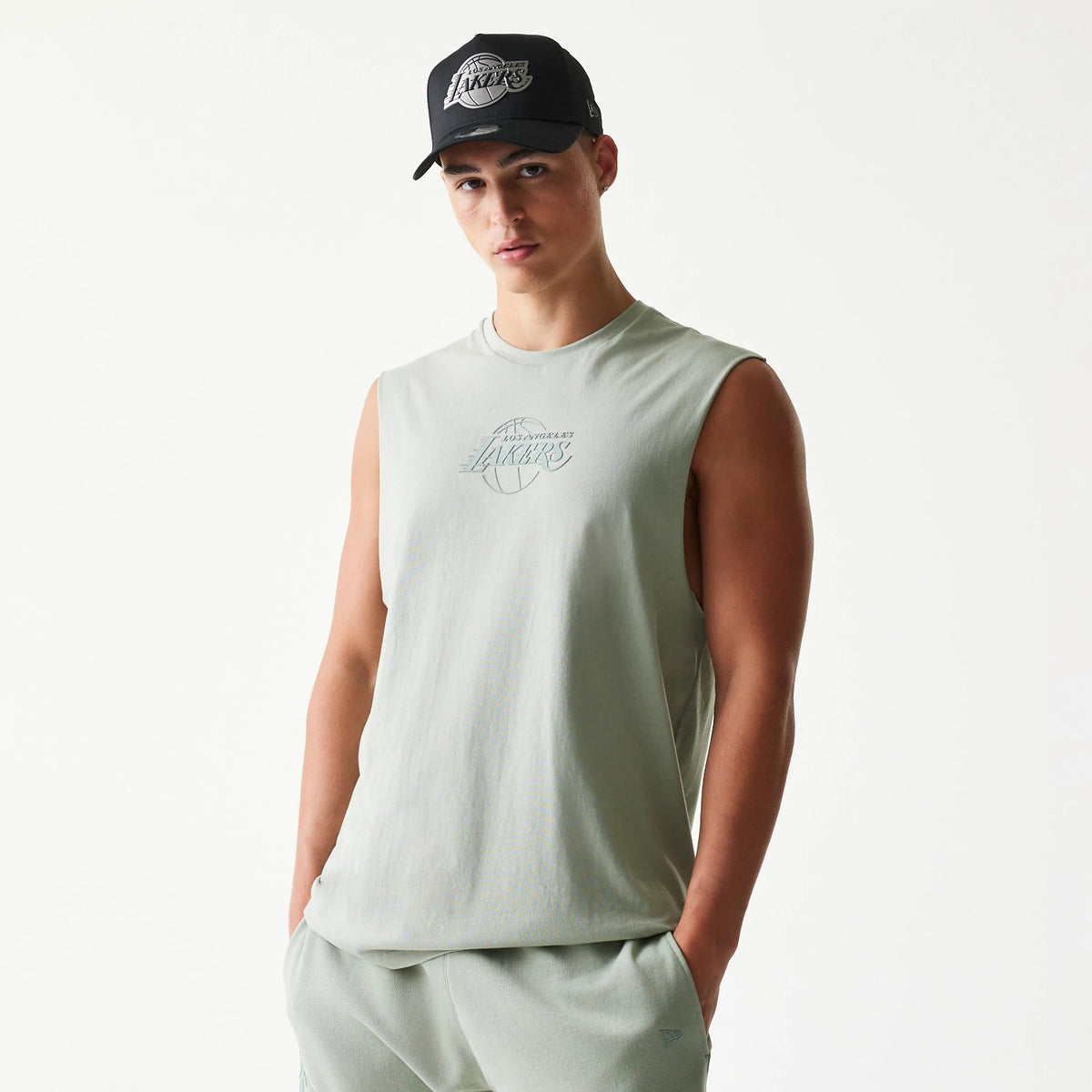 New Era LA Lakers NBA Pastel Green Sleeveless T-Shirt, front view on-model showing a pastel green design, an outlined Lakers logo in the centre, and a New Era logo above the hem with sleeveless styling.