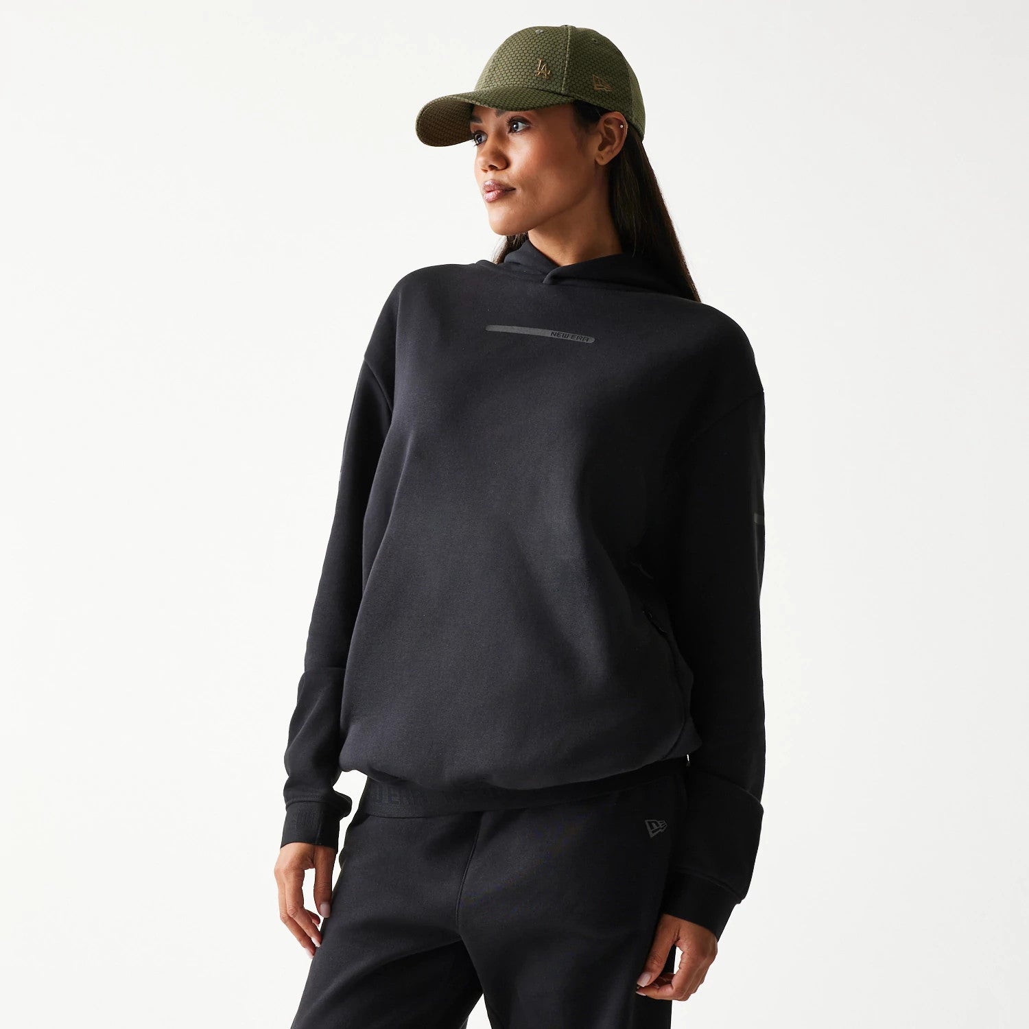 The model is wearing this New Era Tech Strip Oversized Pullover Hoodie in black. 4