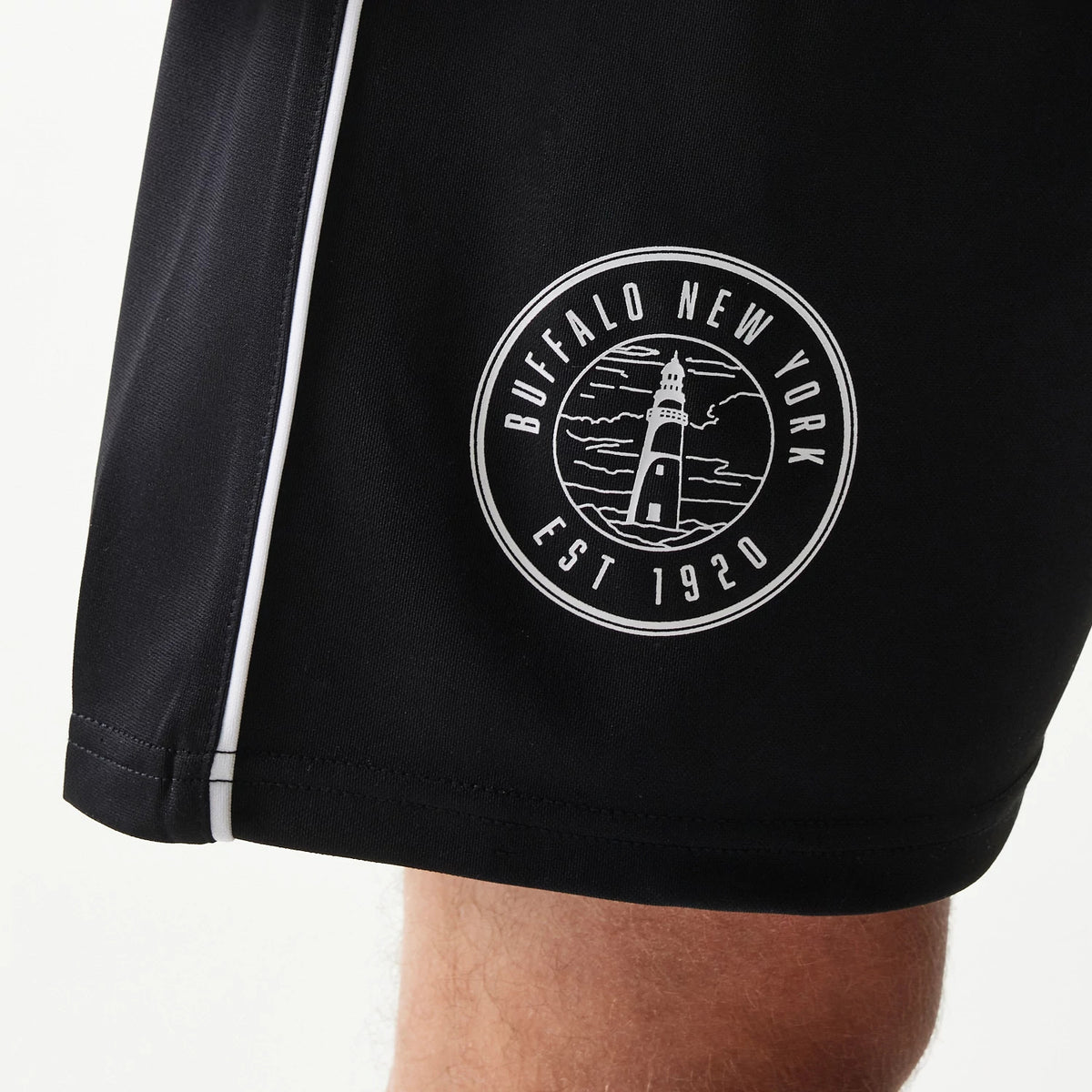 New Era Football Black Shorts, front view showing a white embroidered circular logo featuring the text Buffalo New York Est 1920 surrounding a lighthouse graphic, with a white side stripe running down the seam.