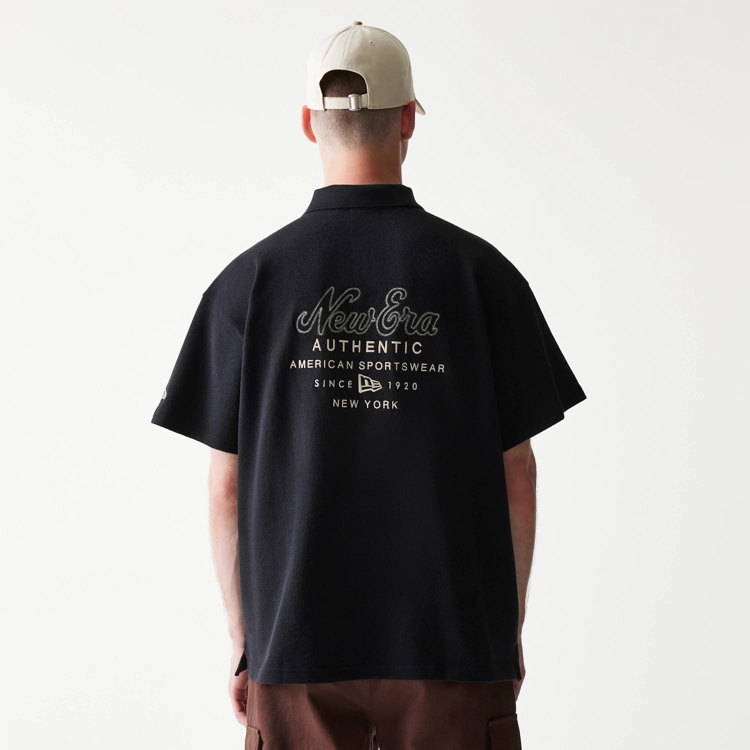 The model is wearing this New Era Graphic Polo T-Shirt in black. 2