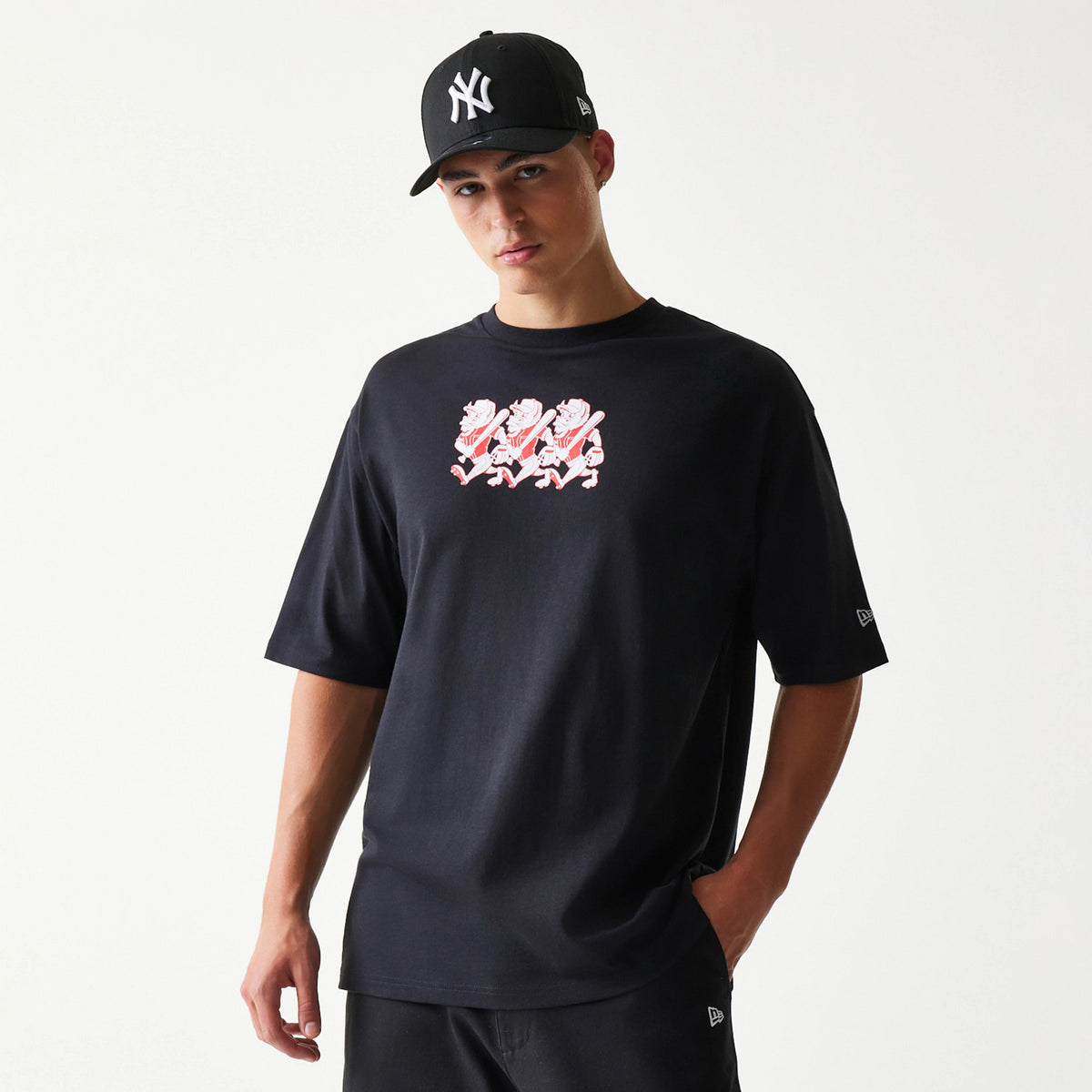New Era Baseball Cows Character Graphic Black Oversized T-Shirt, front view showing a playful white and red cow graphic across the chest, with the New Era embroidered logo on the left sleeve, styled with a black cap.