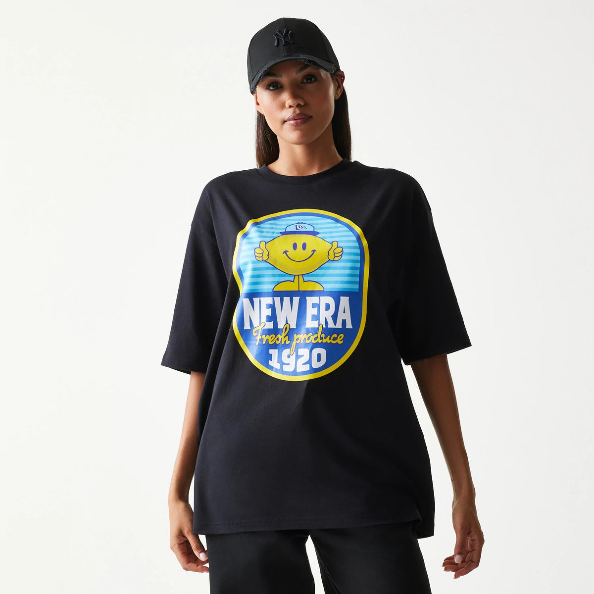 New Era Lemon Fruit Graphic Black Oversized T-Shirt, front view on-model featuring a graphic of a smiling lemon with New Era Fresh Produce 1920 emblazoned across the chest in blue and yellow.