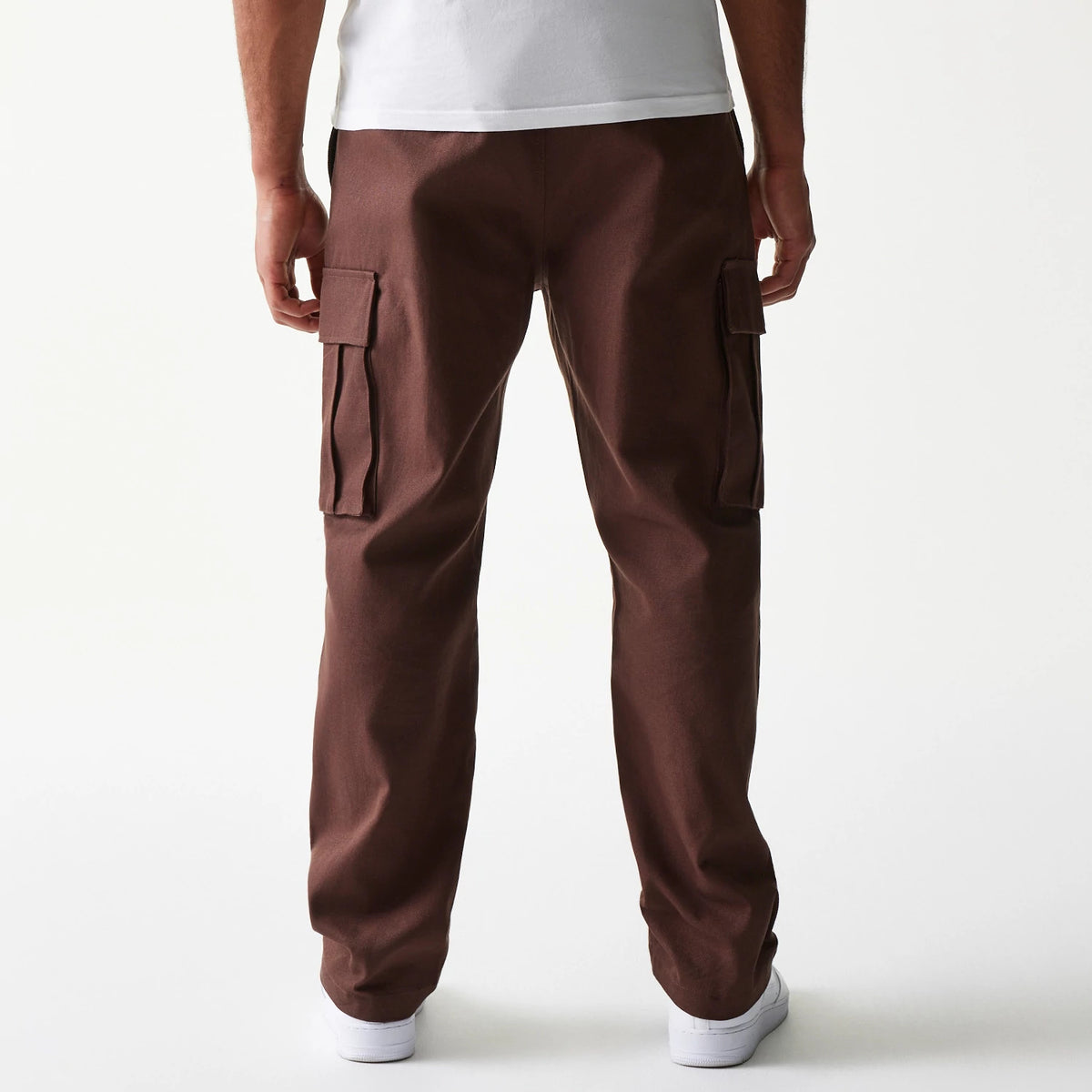 New Era Brown Straight Leg Cargo Joggers, rear view showing the structured fit with two large flap cargo pockets on the thighs, crafted in a rich brown fabric, styled on a model wearing white shoes.