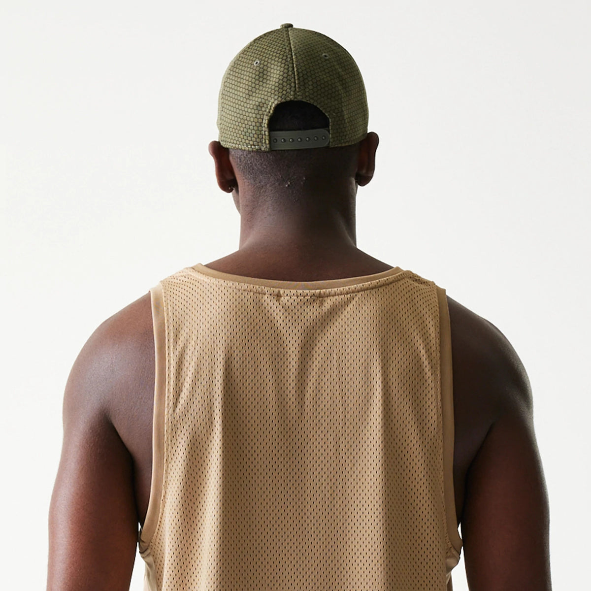 New Era Mesh Light Beige Tank Top, back view on a model highlighting the lightweight mesh fabric structure and light beige colour with wide armholes and a relaxed fit.