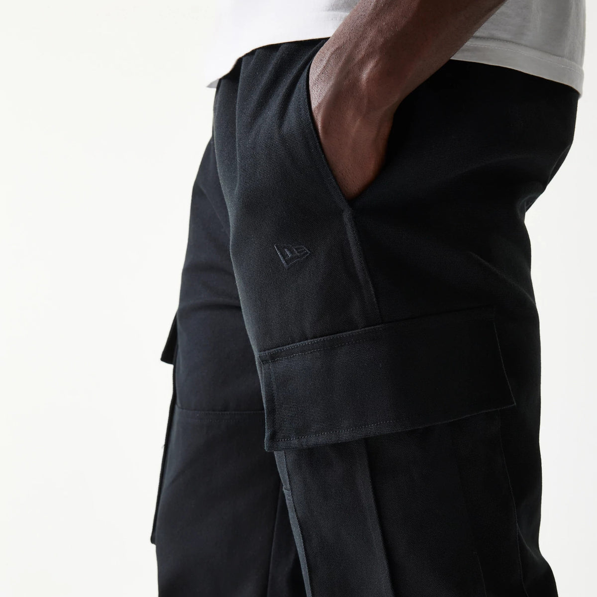 New Era Black Straight Leg Cargo Joggers, side view showing the black New Era flag logo above the right cargo pocket, with hand pockets and stitching details on the black fabric.
