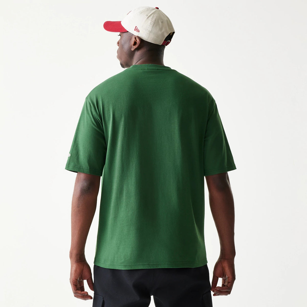 New Era Pear Fruit Graphic Dark Green Oversized T-Shirt, back view showing the plain dark green fabric without graphics, worn by a person with a contrasting cap, highlighting the relaxed fit and loose sleeves.