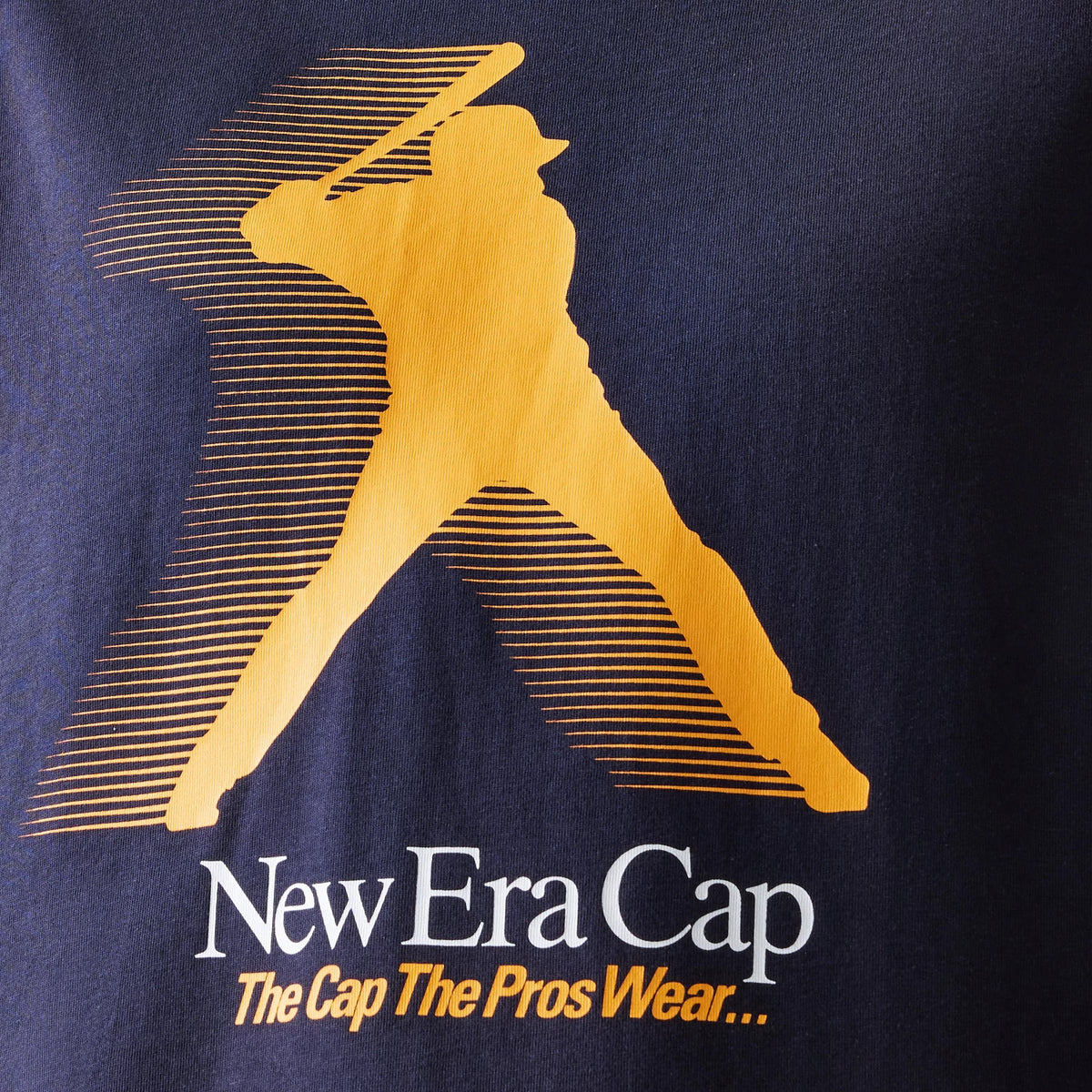 New Era Baseball Player Graphic Navy Oversized T-Shirt, front view showing a large orange silhouette of a batter in action with stylised lines, below which are the words New Era Cap The Cap The Pros Wear... in orange and white lettering.