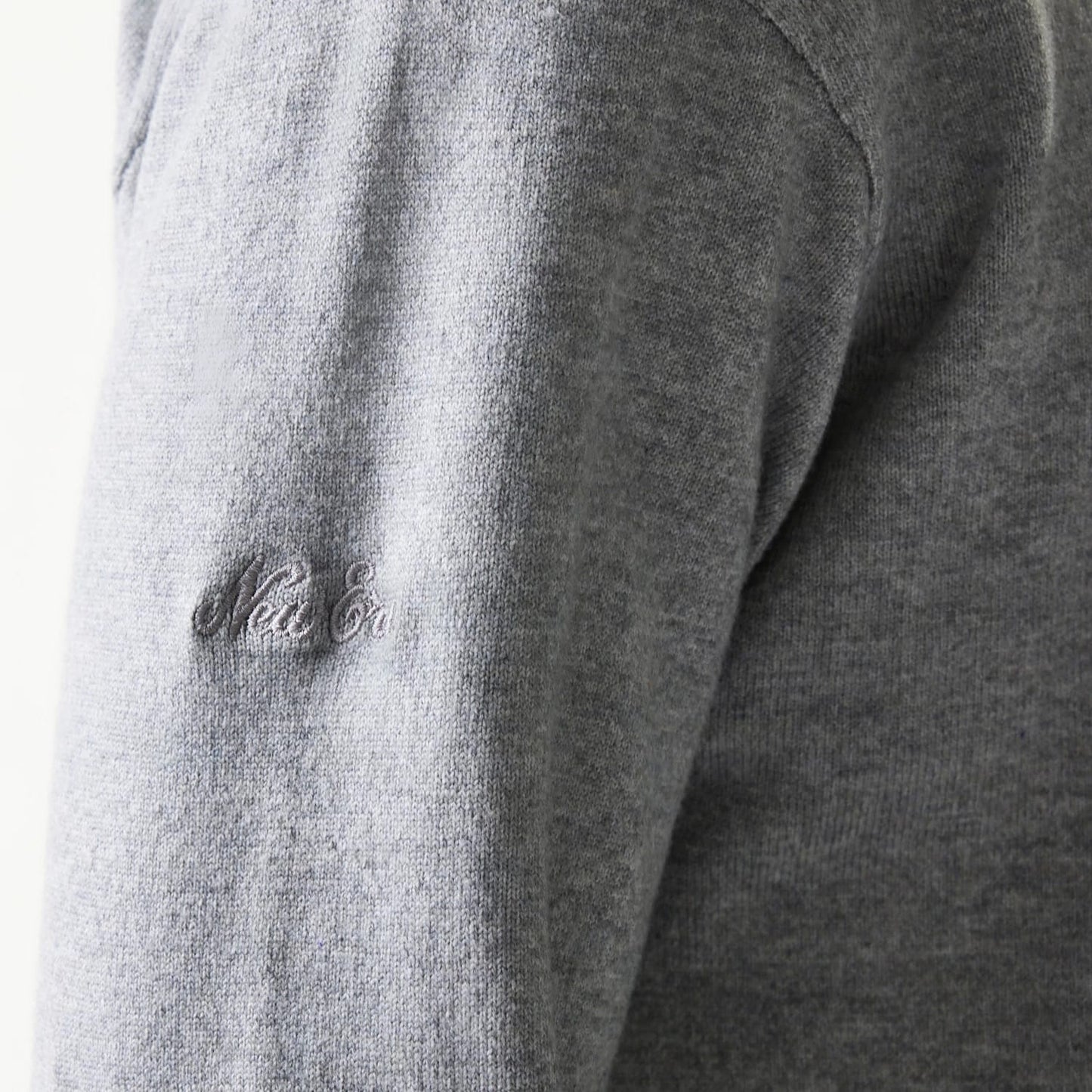 New Era Essential Flag Grey Knitted Sweater, close-up showing the embroidered New Era logo in matching grey thread on the sleeve, highlighting the soft texture and fine knit of the fabric.