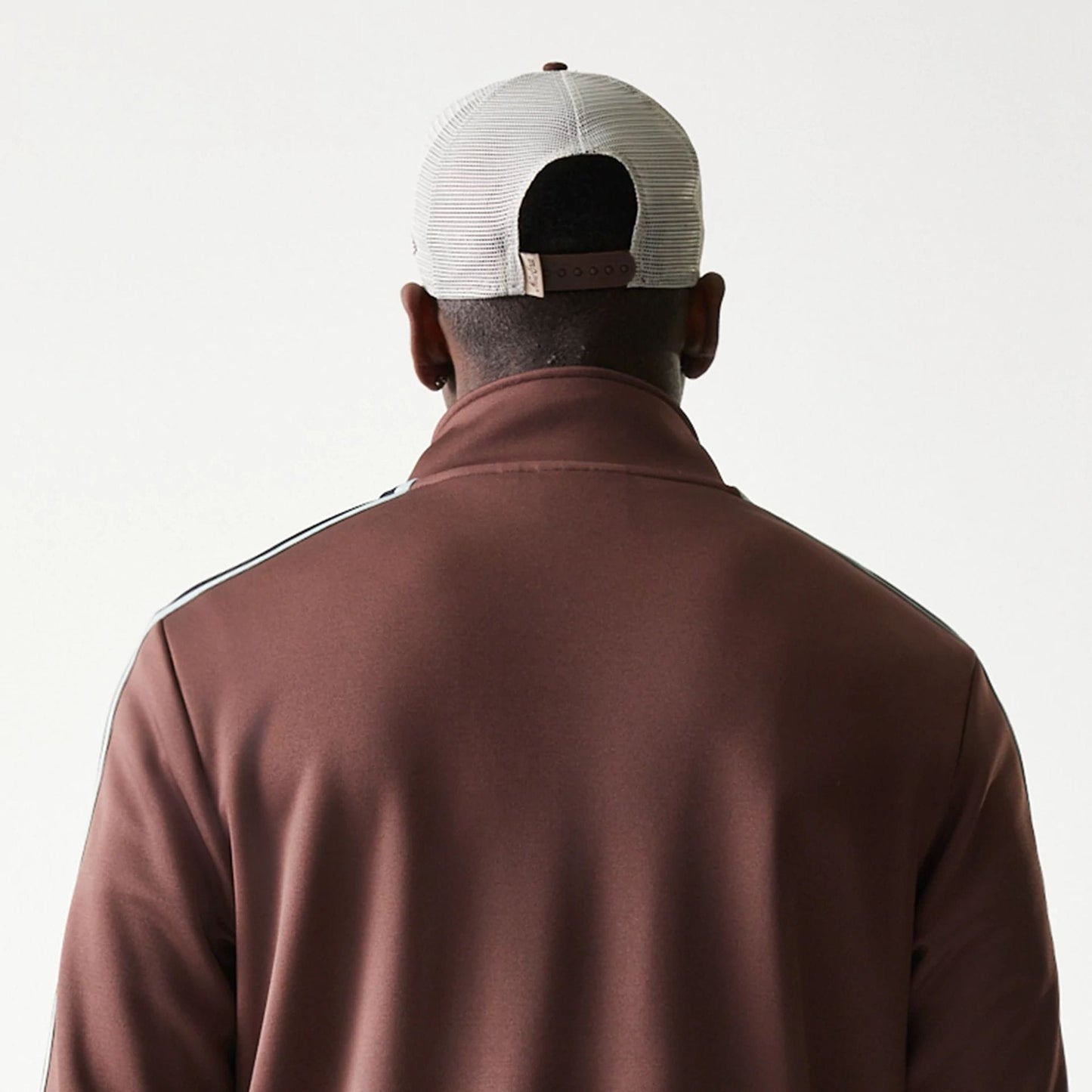 The model is wearing this New Era Script Track Jacket in brown. 8
