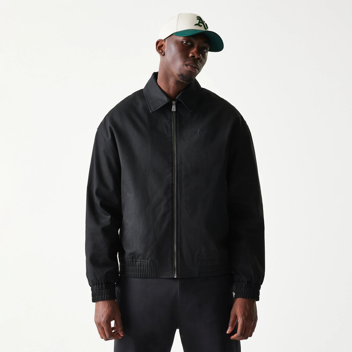 New Era Collared Black Jacket, front view on-model showing a black design with a full zip closure, a embossed New Era logo on the chest, and a structured collar paired with a white cap.