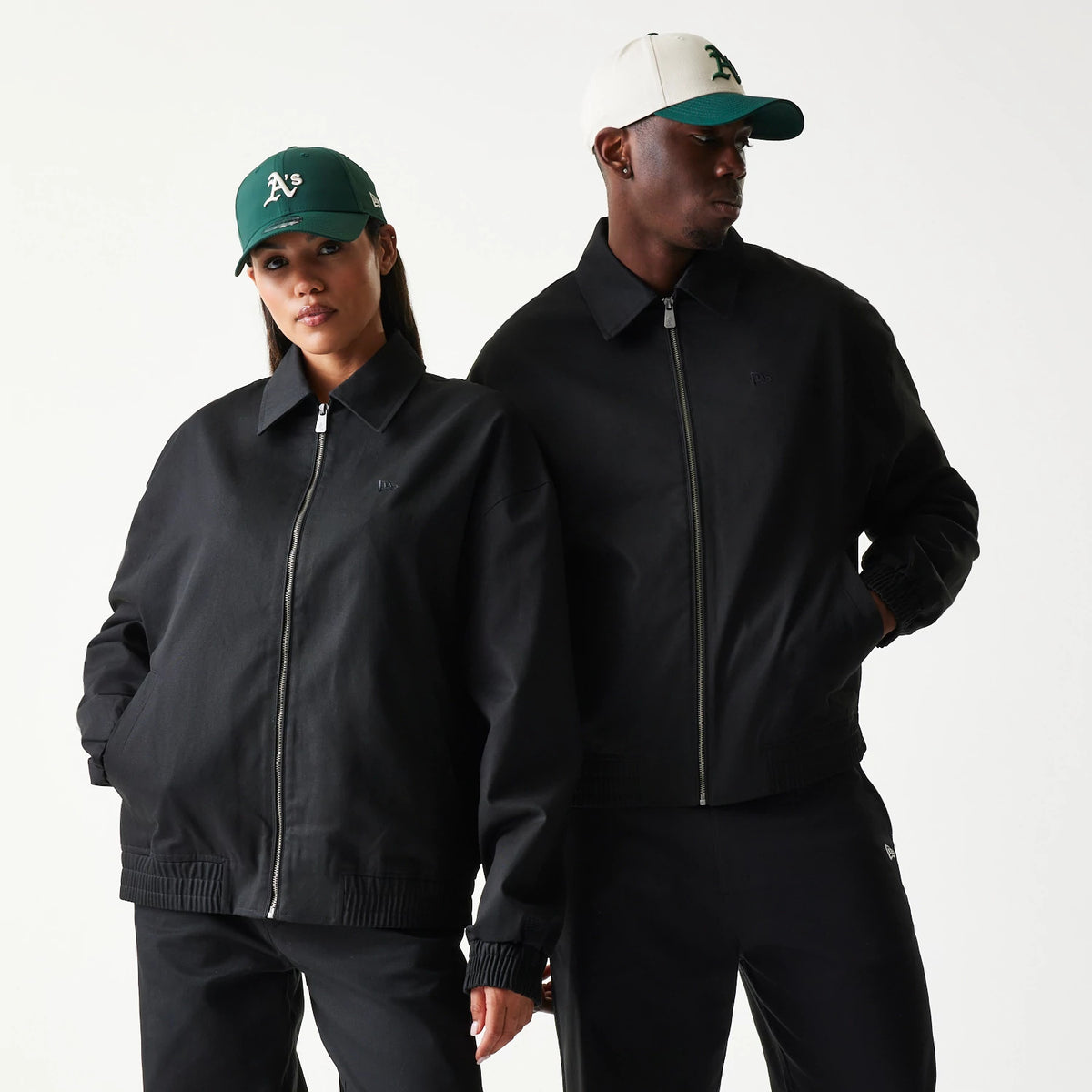 New Era Collared Black Jacket, front view on a model with a green cap, featuring a full-length zip at the centre, a embroidered New Era logo on the left chest, ribbed cuffs, and a straight hemline.
