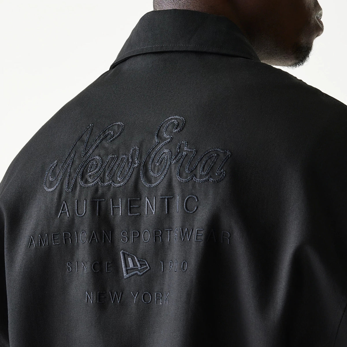 New Era Collared Black Jacket, back view highlighting the raised New Era logo across the upper back followed by embroidered words Authentic American Sportswear Since 1920 New York beneath, worn by a model.