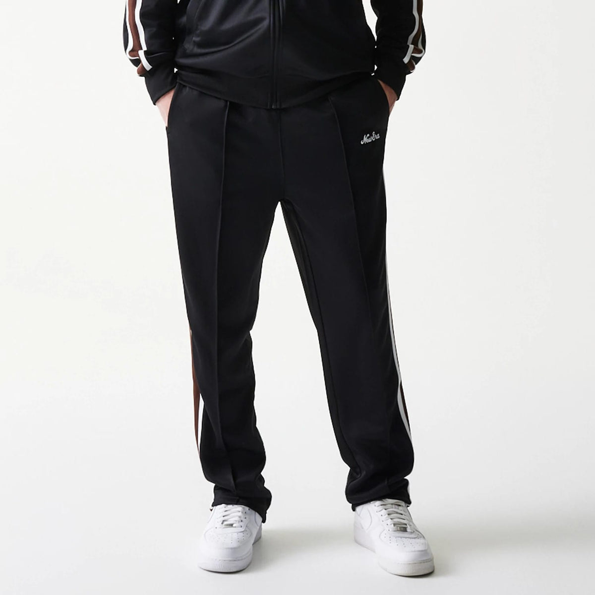 New Era Script Black Straight Leg Joggers, front view showing the white New Era script logo on the left pocket area, with side strip and a relaxed fit around the ankles paired with white trainers.