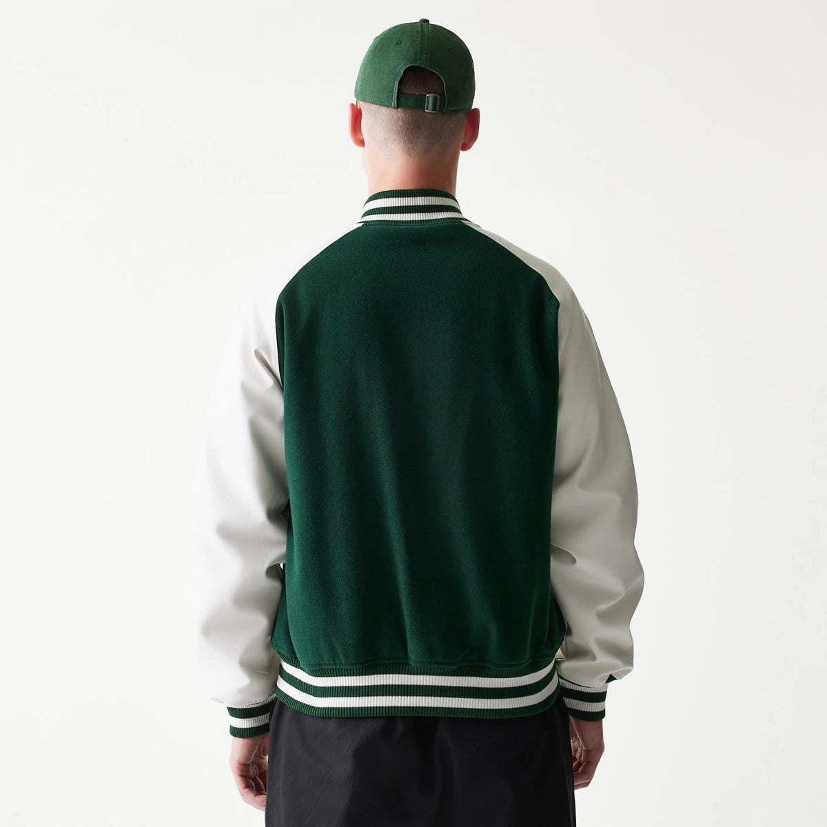 New Era LA Dodgers MLB Dark Green Varsity Jacket, back view on a model with a green cap, showing the dark green back panel and white sleeves, accented by striped cuffs and collar in green and white.