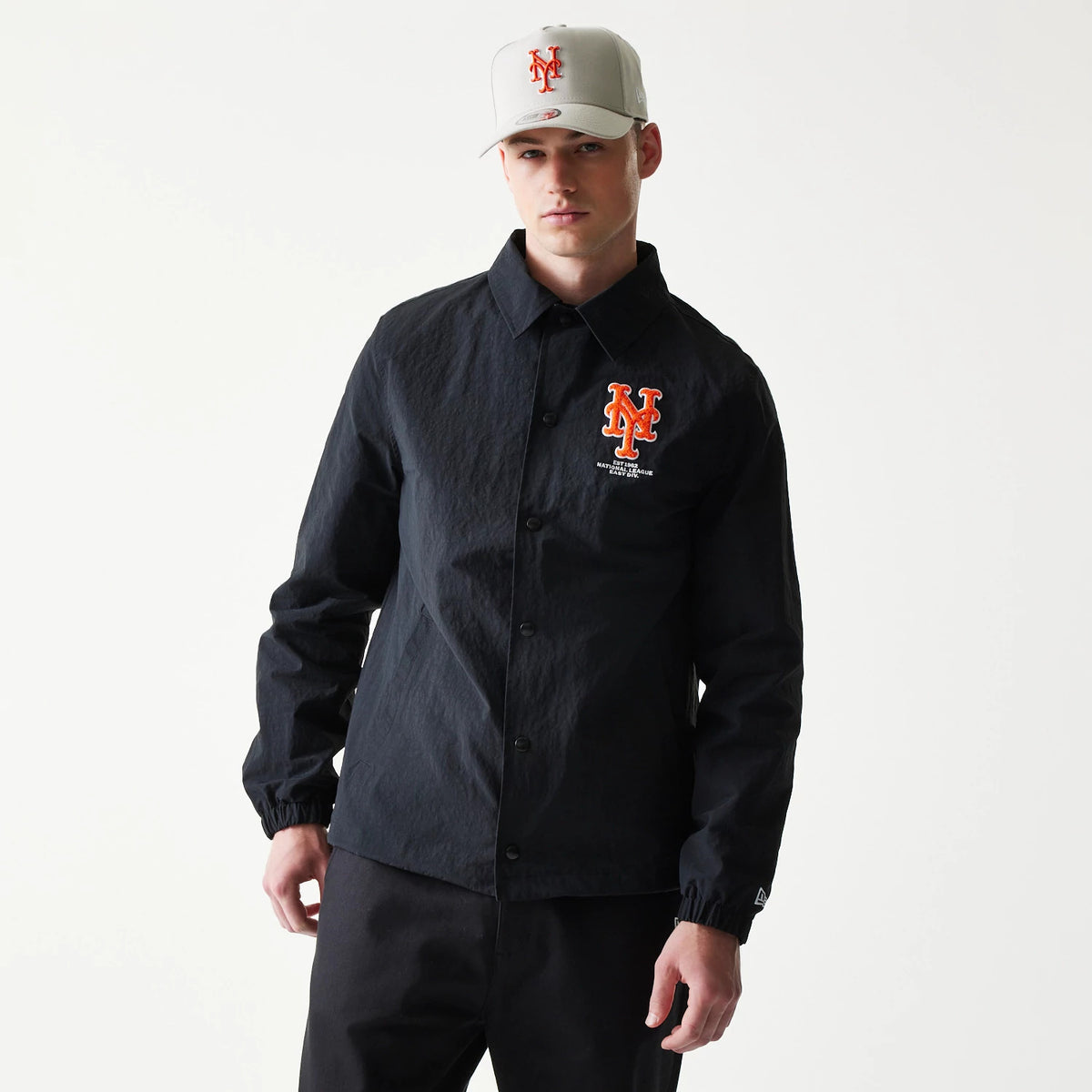 New Era New York Mets MLB Coaches Black Jacket, front view on a model showing the orange embroidered Mets logo on the left chest, with a button-up fastening and a small New Era logo on the left sleeve cuff.