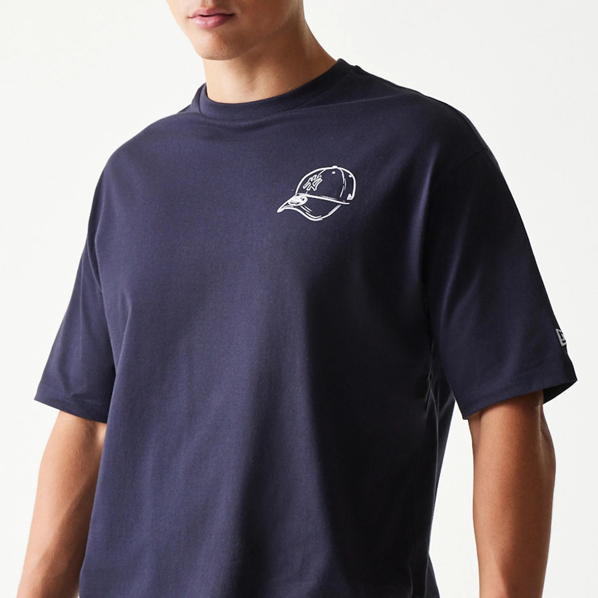New Era New York Yankees MLB Baseball Graphic Navy Oversized T-Shirt, front view on-model showing a white printed graphic of a cap with the Yankees logo on the left chest and an embroidered New Era logo on the left sleeve.