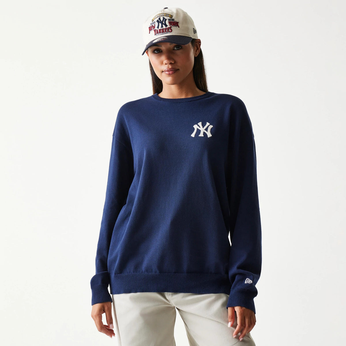 New Era New York Yankees MLB Essential Navy Knitted Sweater, front view on a model with a matching cap, featuring a white embroidered Yankees logo on the left chest and the New Era flag logo on the left sleeve cuff.