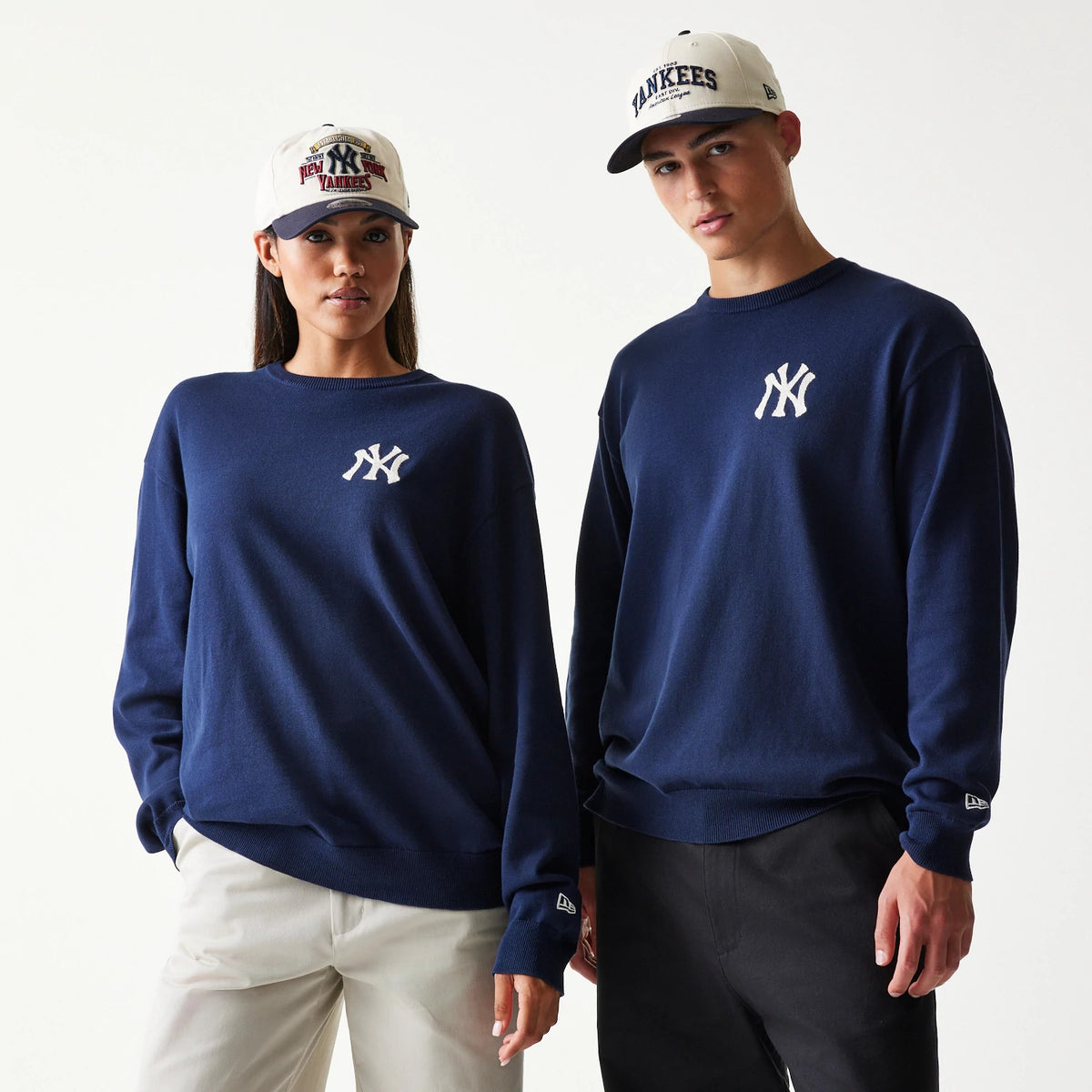 New Era New York Yankees MLB Essential Navy Knitted Sweater, front view on models with white Yankees caps, featuring the white embroidered NY logo on the left chest and the New Era flag logo on the left sleeve cuff.