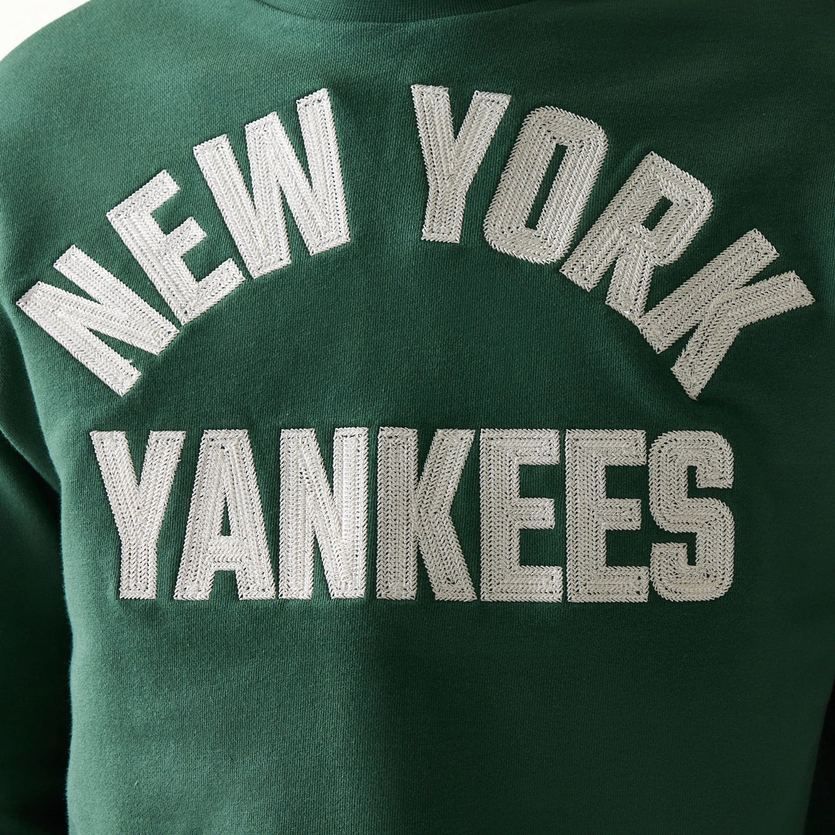 New Era New York Yankees MLB Graphic Dark Green Oversized Crew Neck Sweater, front view showing large white embroidered New York Yankees lettering in an arch on the chest against a dark green background.