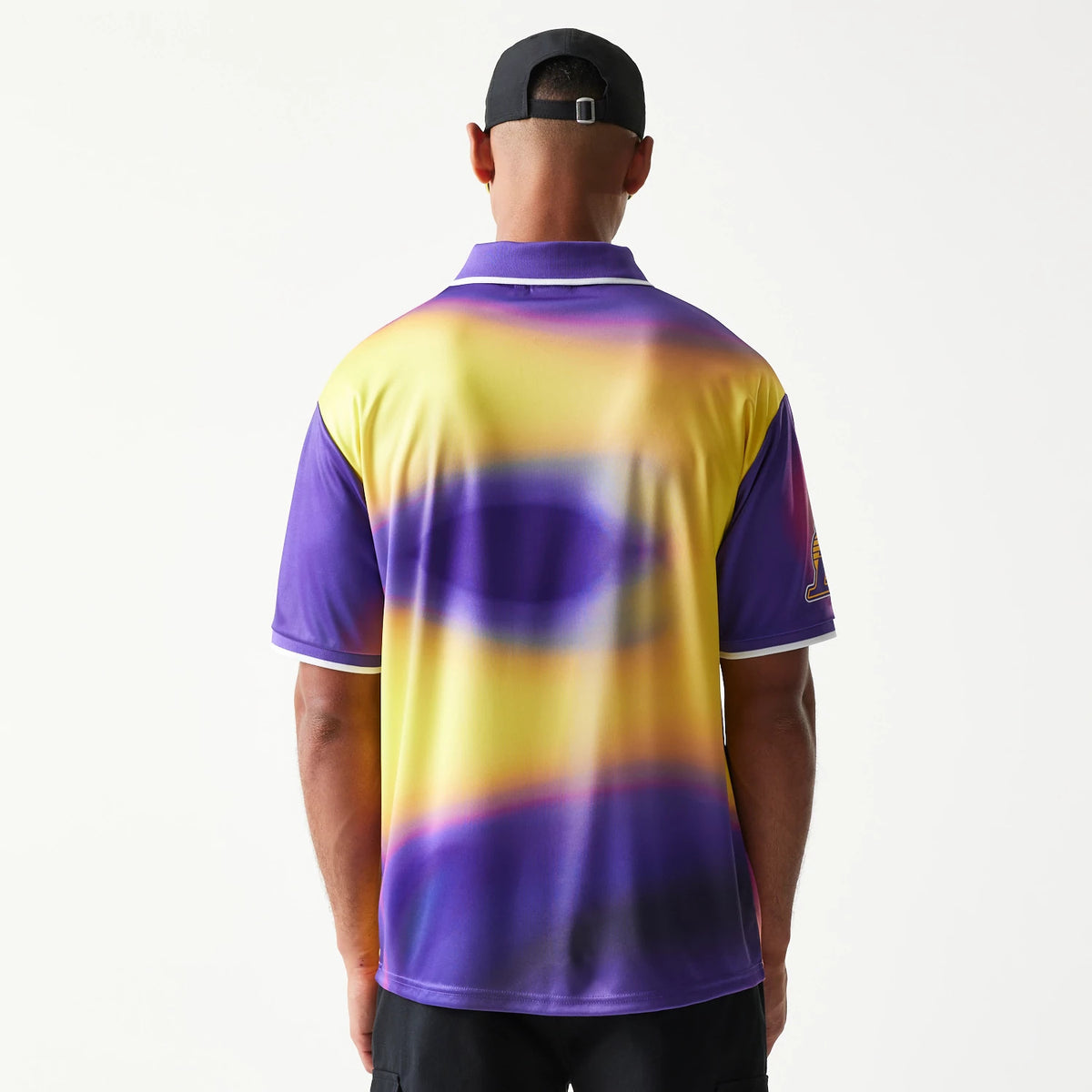 New Era LA Lakers NBA All Over Print Purple T-Shirt, back view with a model wearing the shirt that features a blurred purple and yellow graphic design, showing the purple sleeves and an embroidered Lakers logo on the right.