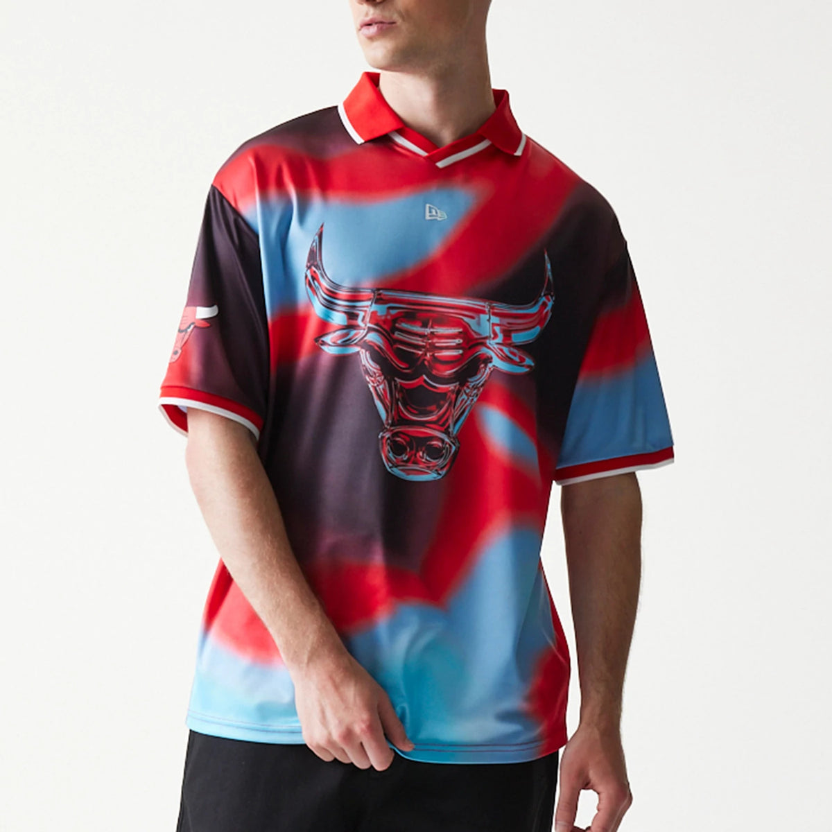 New Era Chicago Bulls NBA All Over Print Red T-Shirt, front view on-model showing a large central bull graphic with red and blue tie-dye patterning, an embroidered New Era logo below the collar and a team logo on the left sleeve.