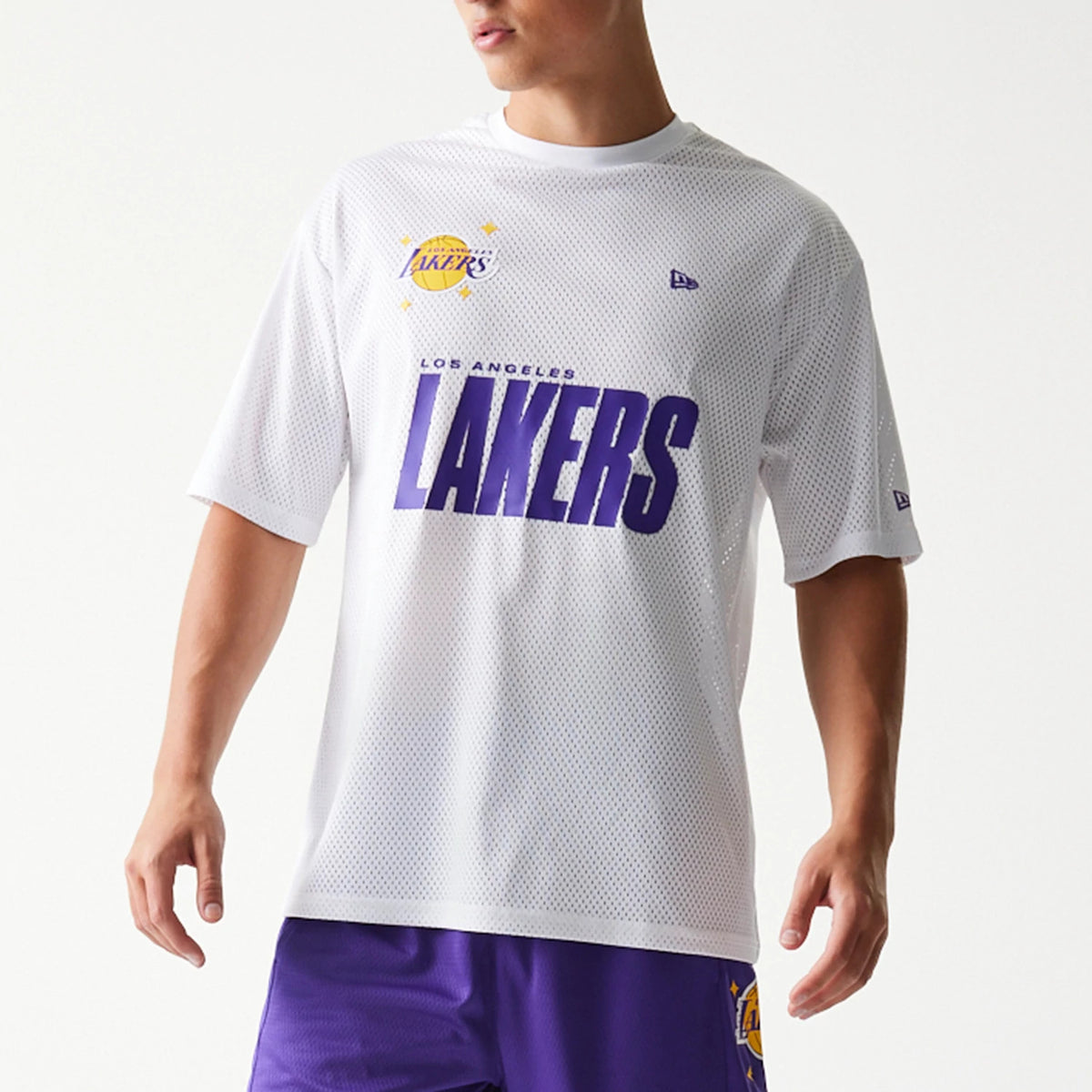 New Era LA Lakers NBA Graphic Mesh White T-Shirt, front view on-model showing the large purple Lakers lettering across the chest, a printed team logo above on the left side, and a small embroidered New Era logo on the right sleeve.