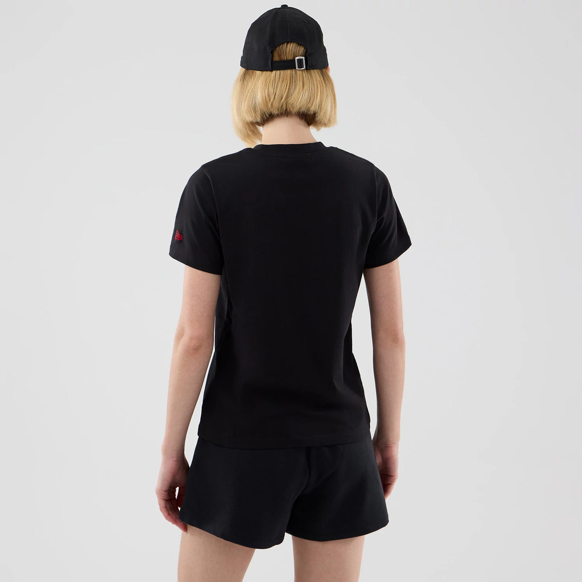 New Era New York Yankees Womens MLB Infill Black T-shirt, back view showing a plain black design with a small red embroidered New Era logo on the left sleeve, styled casually on a model paired with black shorts and a cap.