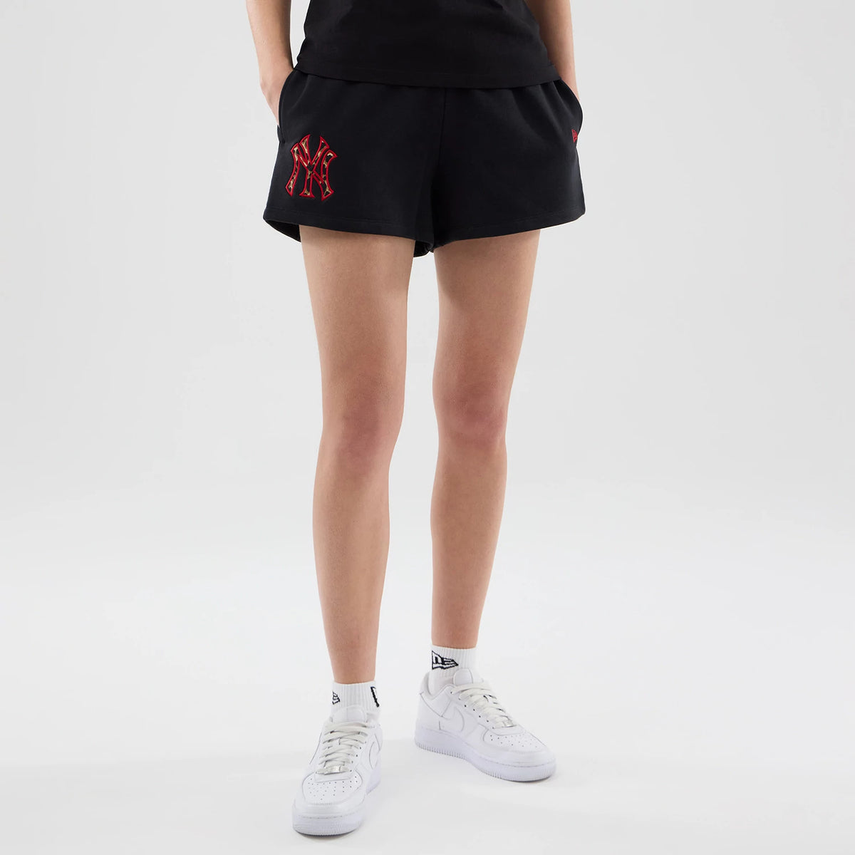 New Era New York Yankees Womens MLB Infill Black Shorts, front view on-model highlighting the embroidered red Yankees logo on the left thigh, styled with a black top and white trainers.