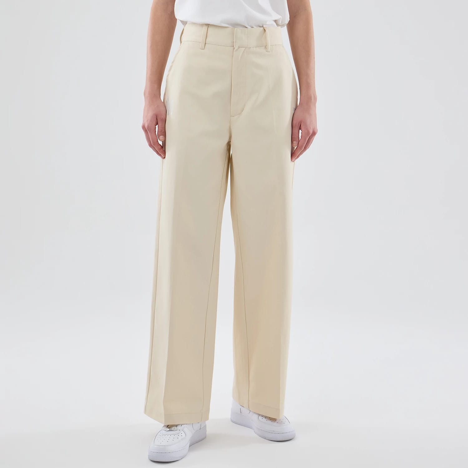 New Era New York Yankees Womens MLB Cream Chino Trousers, front view on a model showing high-waisted trousers with belt loops, a zip fly, and wide-legged design, paired with white trainers and a tucked-in white top.