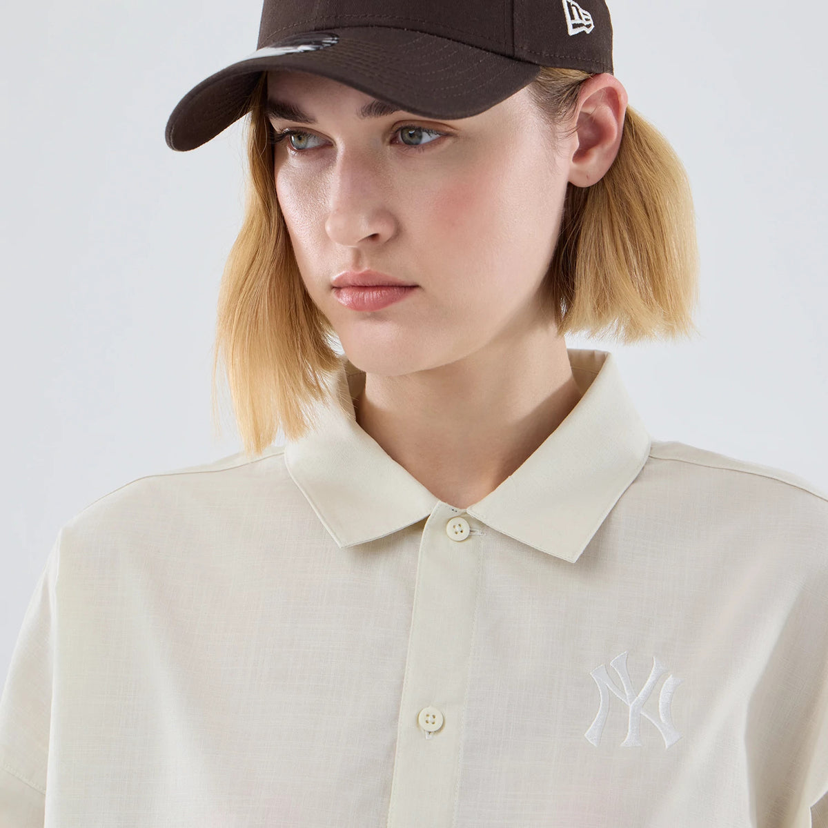 New Era New York Yankees Womens MLB Shirt Cream Long Sleeve Shirt, front view on a model wearing a brown cap, showing an embroidered white Yankees logo on the left chest with a classic collar and button placket.