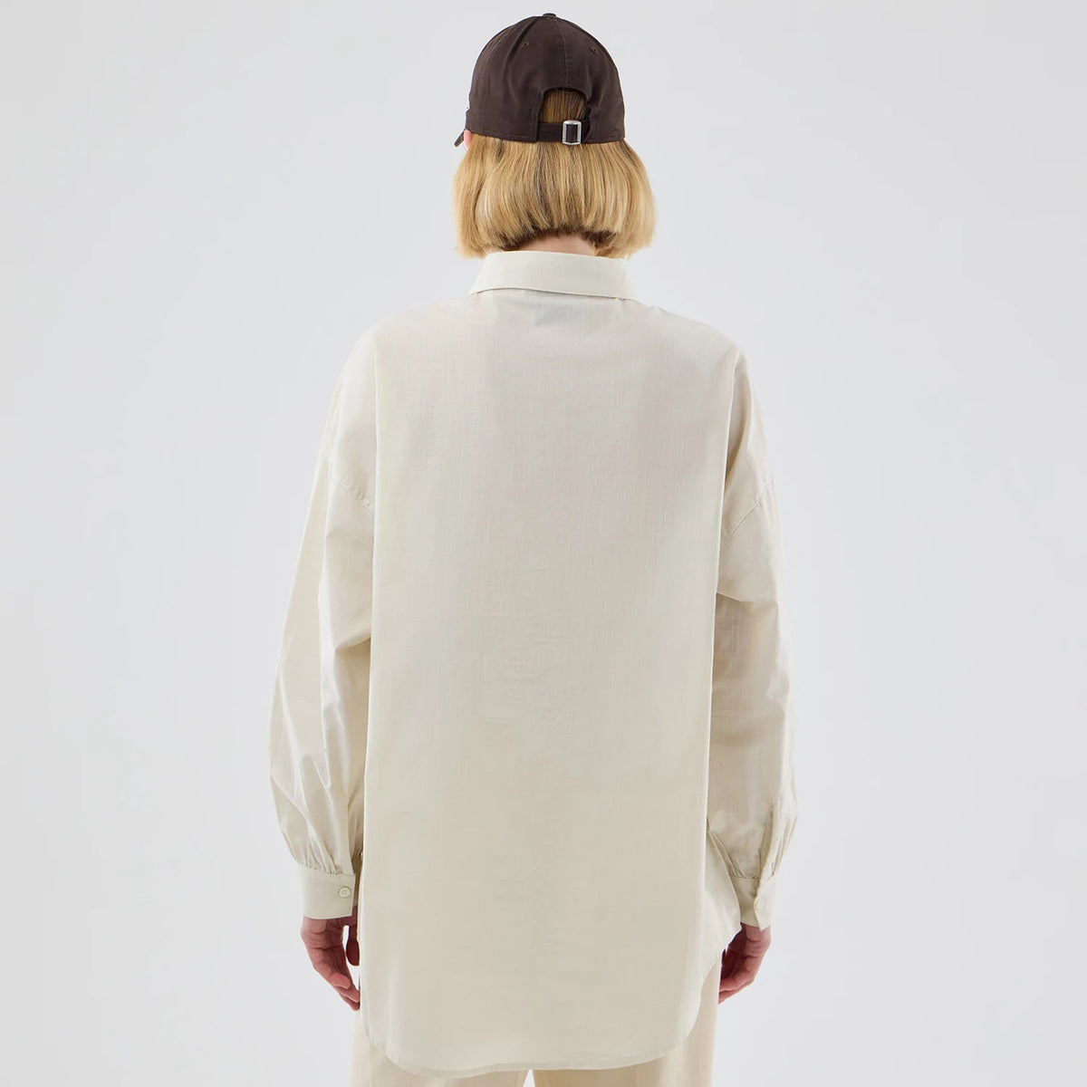 New Era New York Yankees Womens MLB Shirt Cream Long Sleeve Shirt, back view on a model wearing a cap, showing the loose fit and extended hemline of the cream shirt with buttoned cuffs and a classic collar.