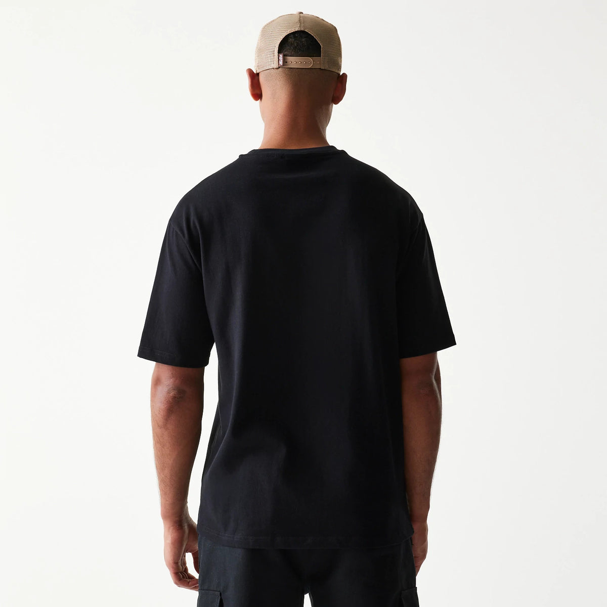 New Era Heritage Script Black T-Shirt, back view showing the plain black shirt with a relaxed fit on a model wearing a contrasting cap, highlighting a simple, clean design with no graphics or logos.