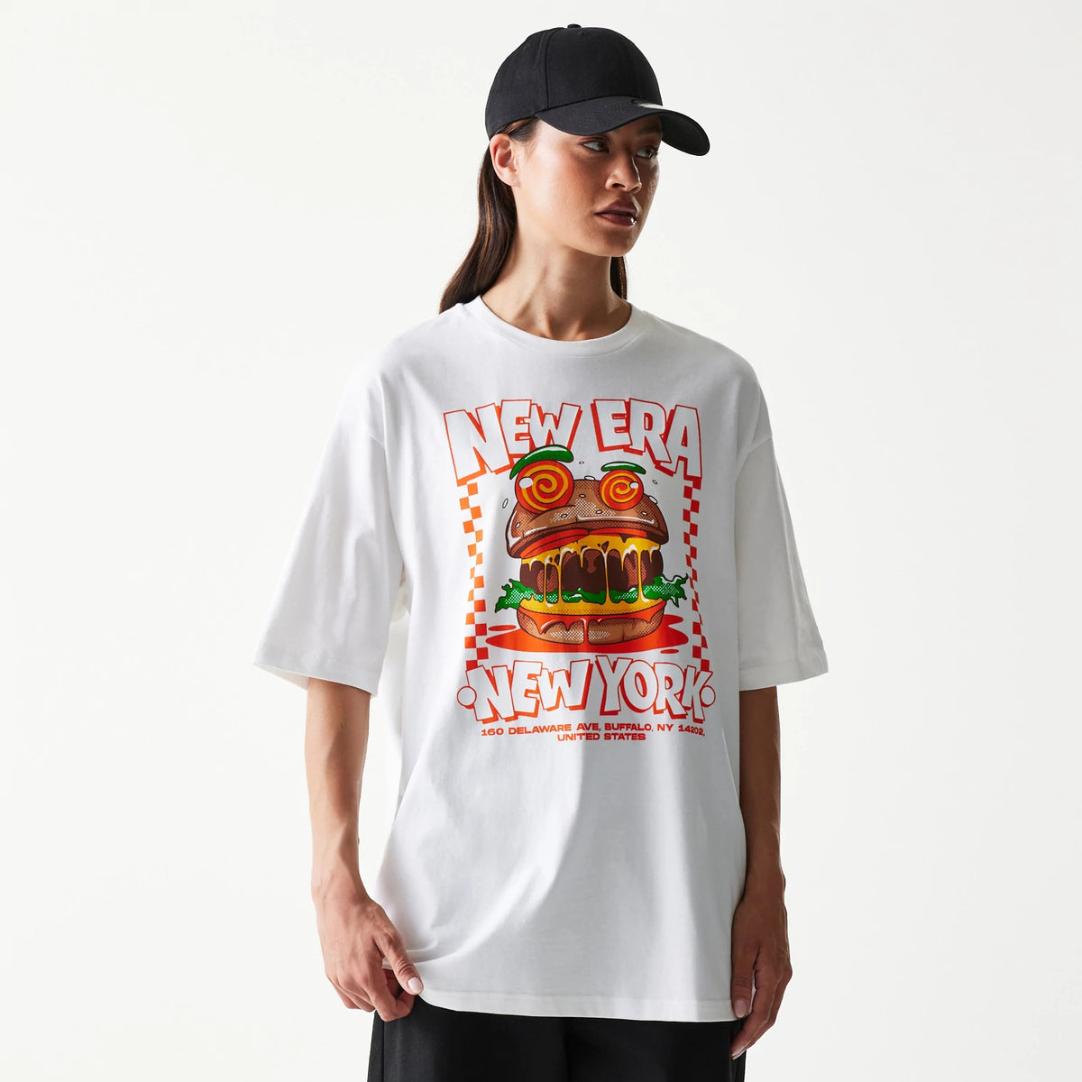 New Era Burger Food Graphic White Oversized T-Shirt, front view on-model featuring a graphic of a burger with candy eyes and vegetables, oversized New Era New York lettering above and below the design on a white fabric background.