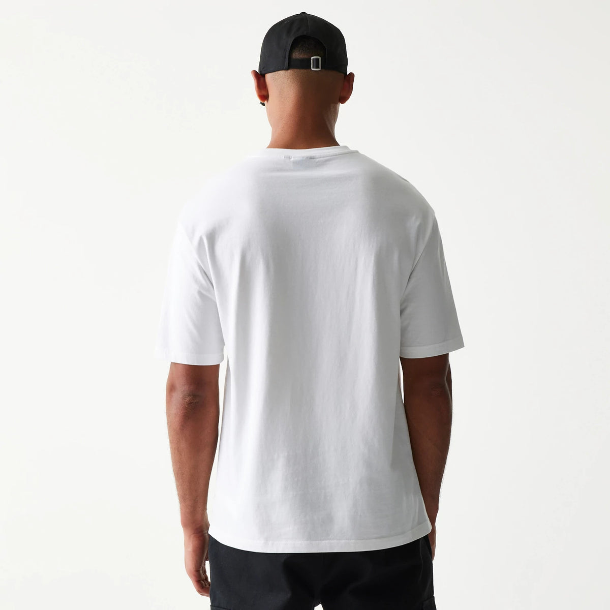 New Era Burger Food Graphic White Oversized T-Shirt, back view on a model with a contrasting black cap, showing the plain white back of the oversized fit shirt with short sleeves extending to the elbows.
