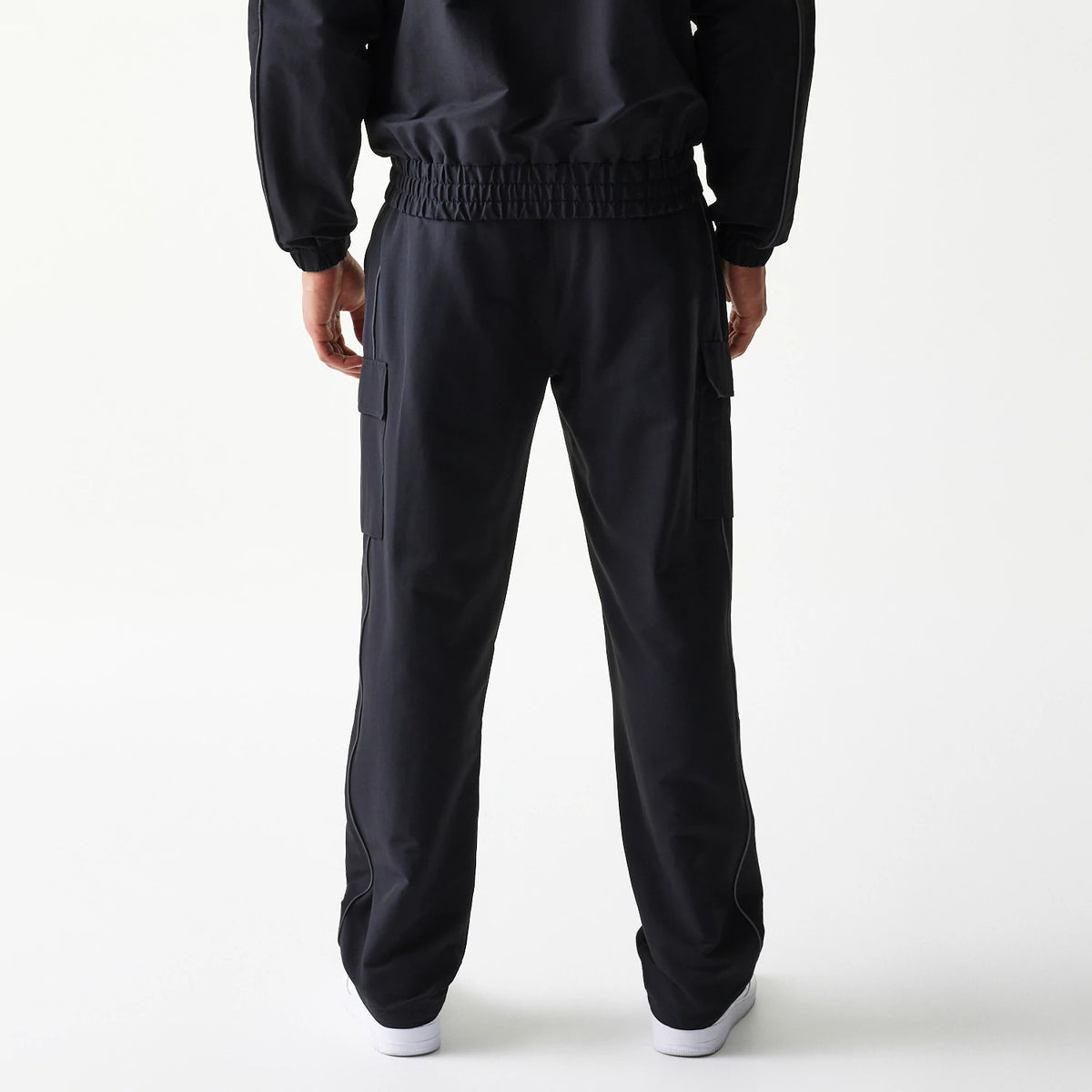 New Era New York Yankees MLB Utility Black Straight Leg Cargo Joggers, rear view on-model showing black elasticated waistband, cargo pockets on the sides, and a relaxed straight-leg fit, styled with a matching black jacket.