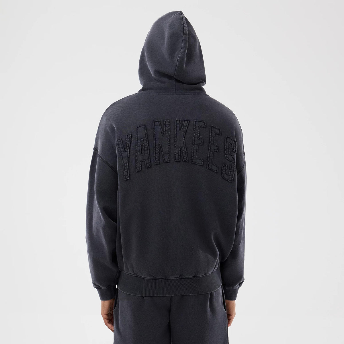 New Era New York Yankees MLB Washed Black Full Zip Hoodie, back view showing large Yankees lettering embroidered across the upper back of the washed black hoodie, with a relaxed fit and ribbed hem at the waist.