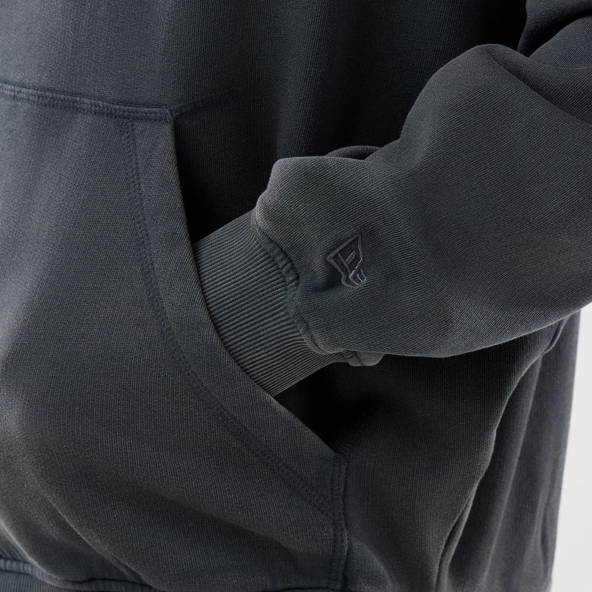 New Era LA Dodgers MLB Washed Dark Grey Full Zip Hoodie, side view showing a close-up of the kangaroo pocket and ribbed cuff with a embroidered New Era logo near the wrist on the dark grey sleeve.
